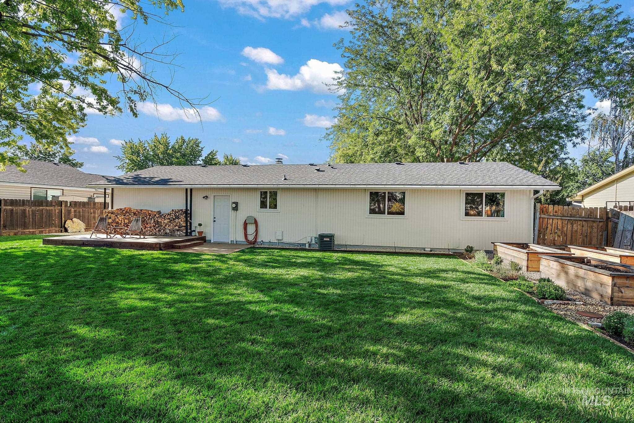 Rear view of house featuring a vegetable garden, roof with shingles, and a patio