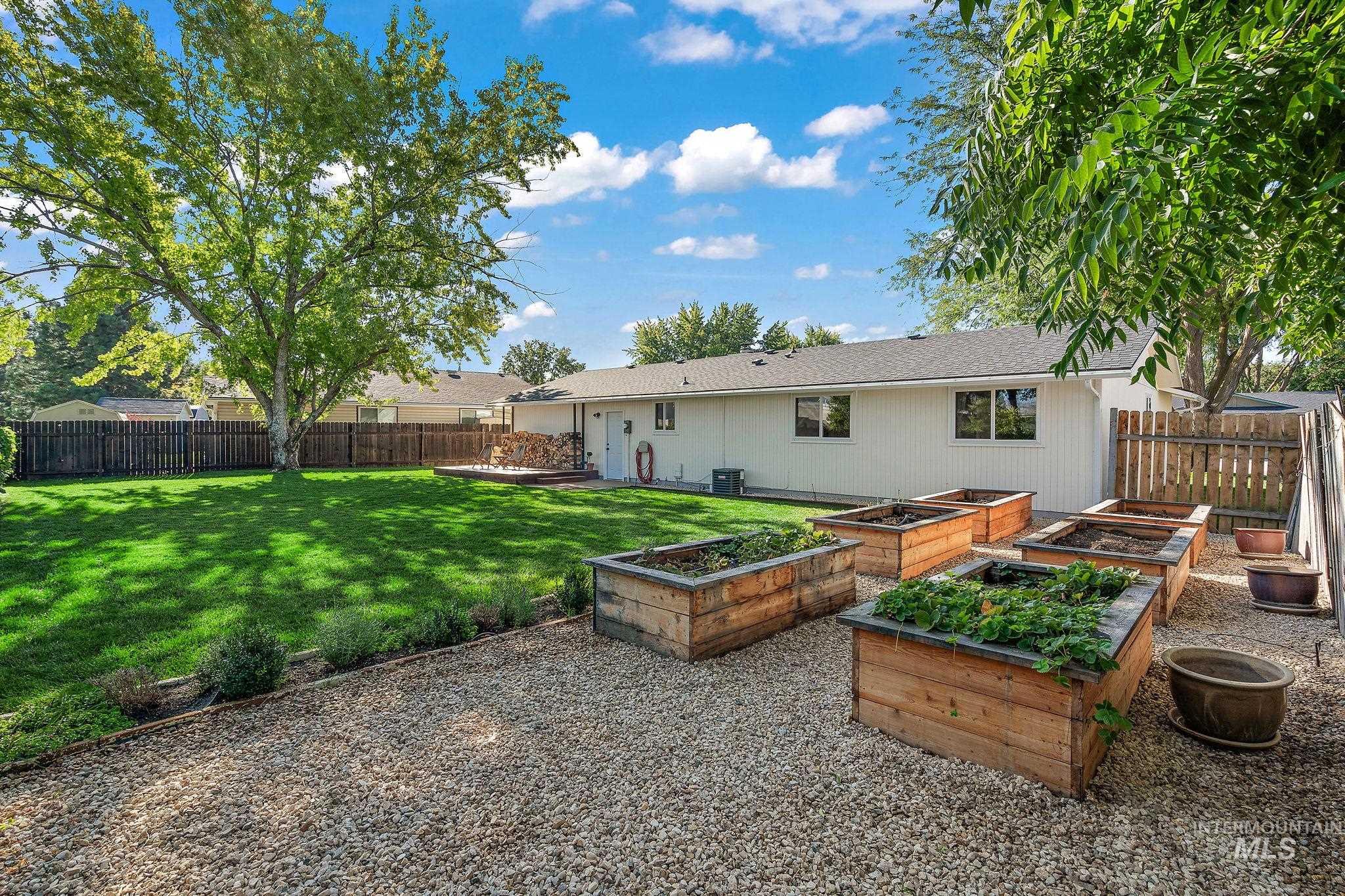 Rear view of house featuring a fenced backyard, a vegetable garden, a shingled roof, and a patio area