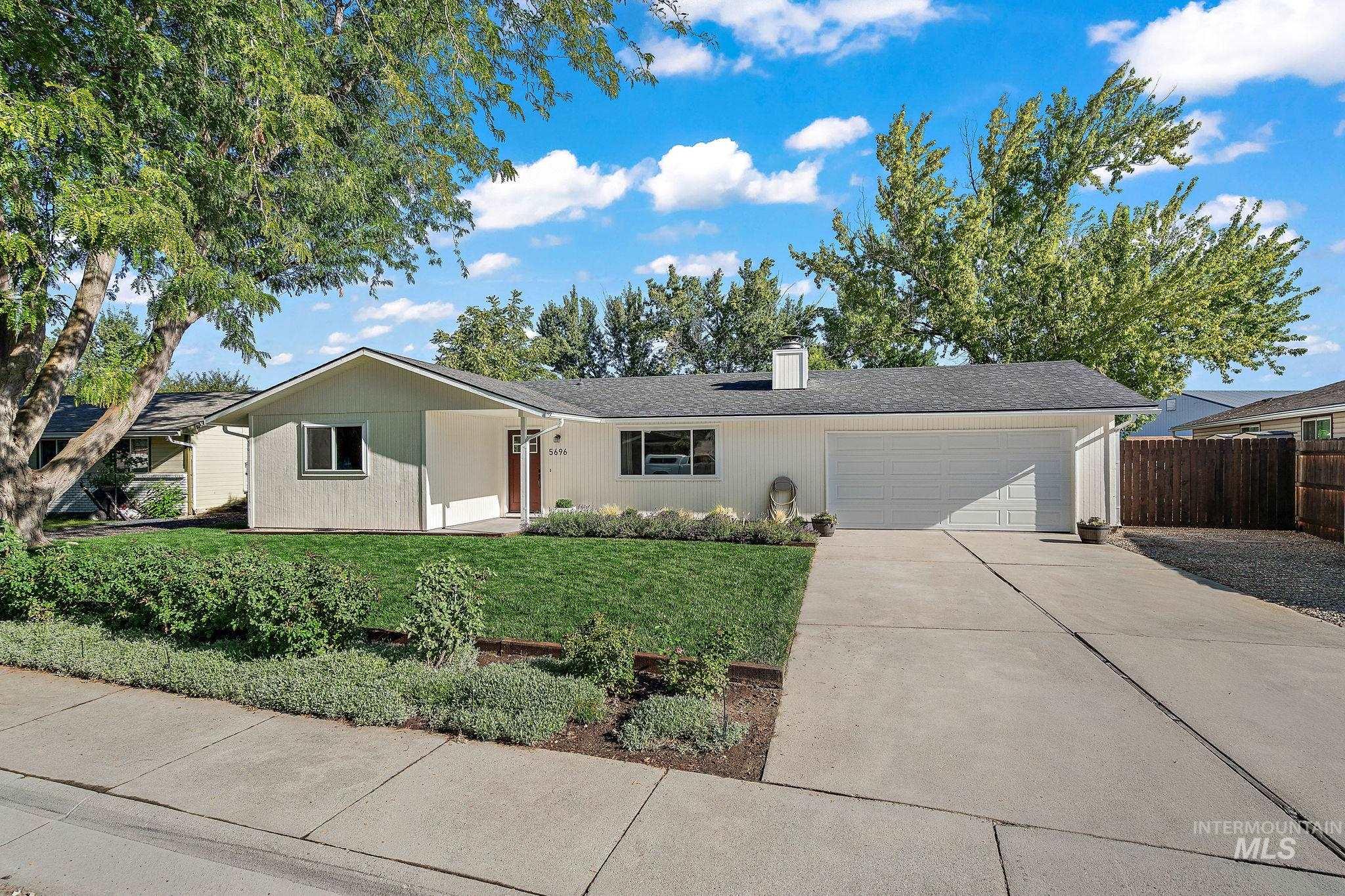 Ranch-style home with concrete driveway, a chimney, and a garage