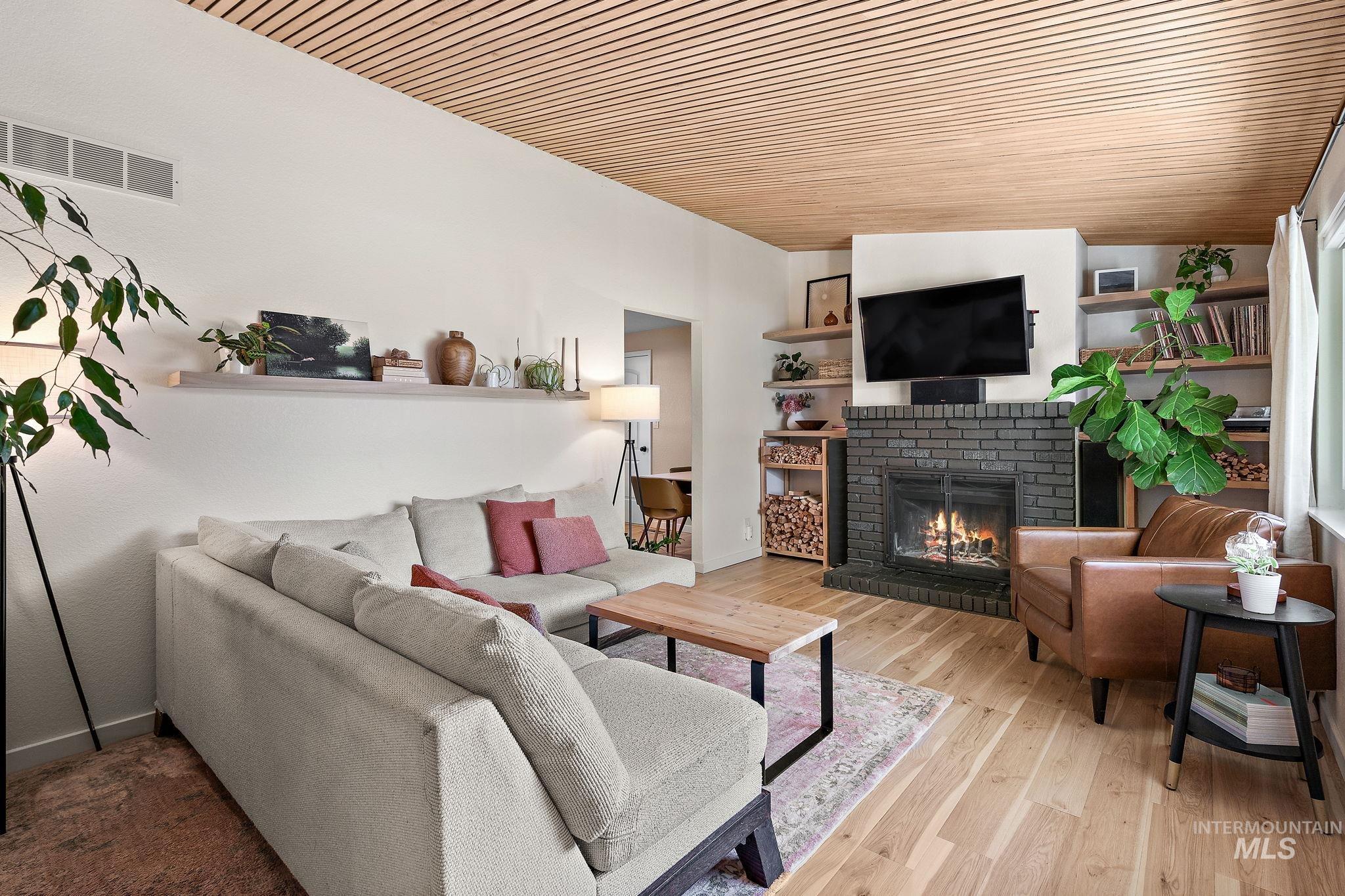 Living room featuring a fireplace, light wood-style floors, and wooden ceiling