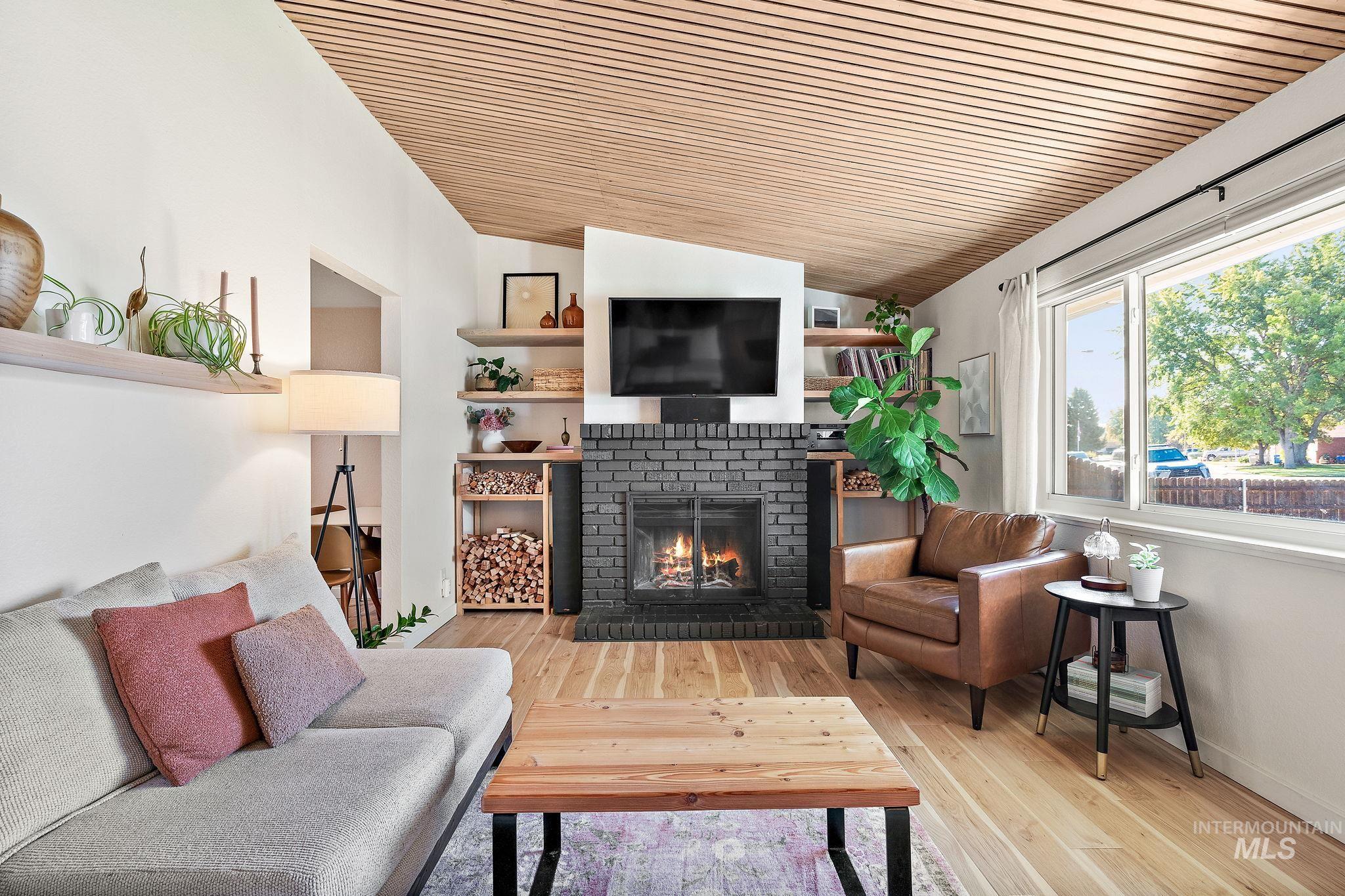 Living room with lofted ceiling, a fireplace, wood finished floors, and wooden ceiling
