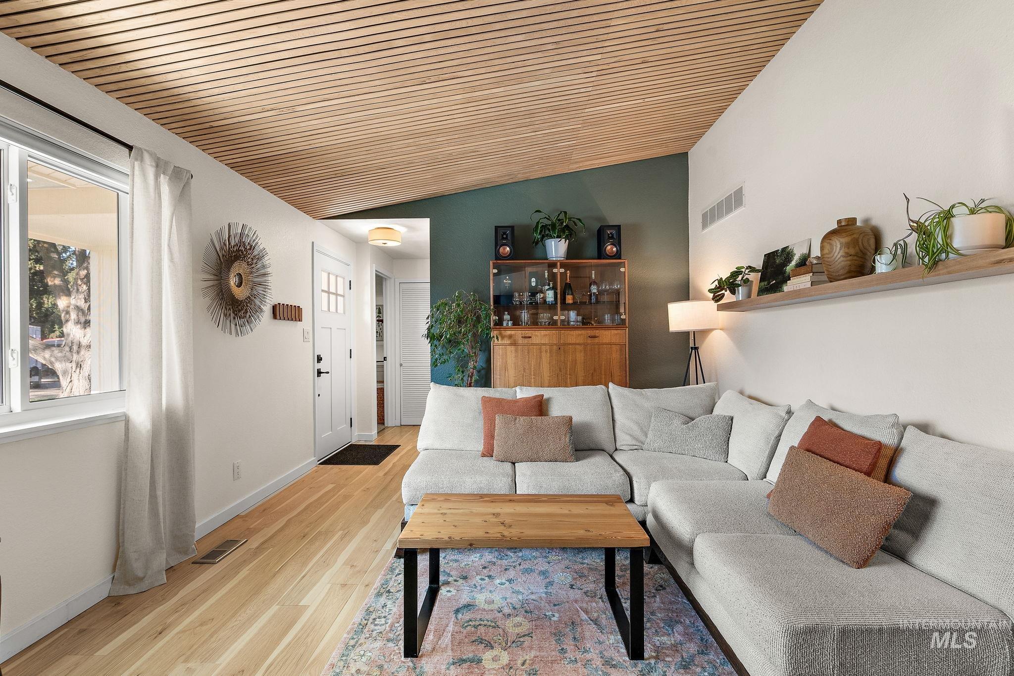Living area with light wood finished floors, vaulted ceiling, and wooden ceiling