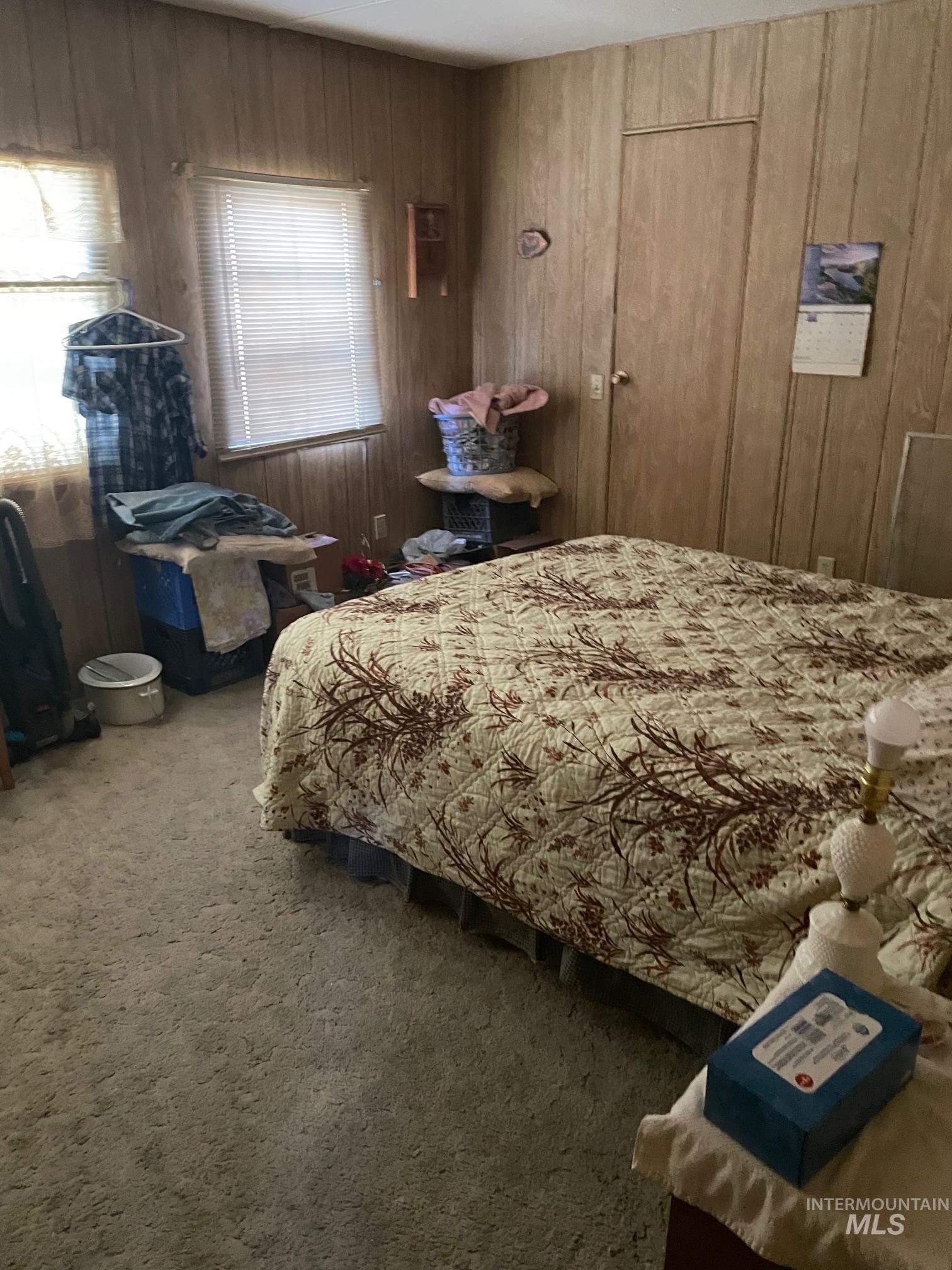 Carpeted bedroom featuring wooden walls