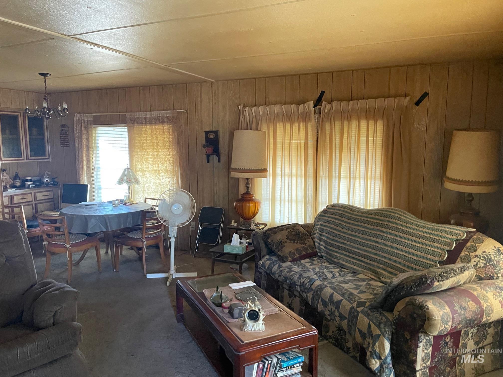 Living room featuring carpet flooring, wooden walls, and a chandelier