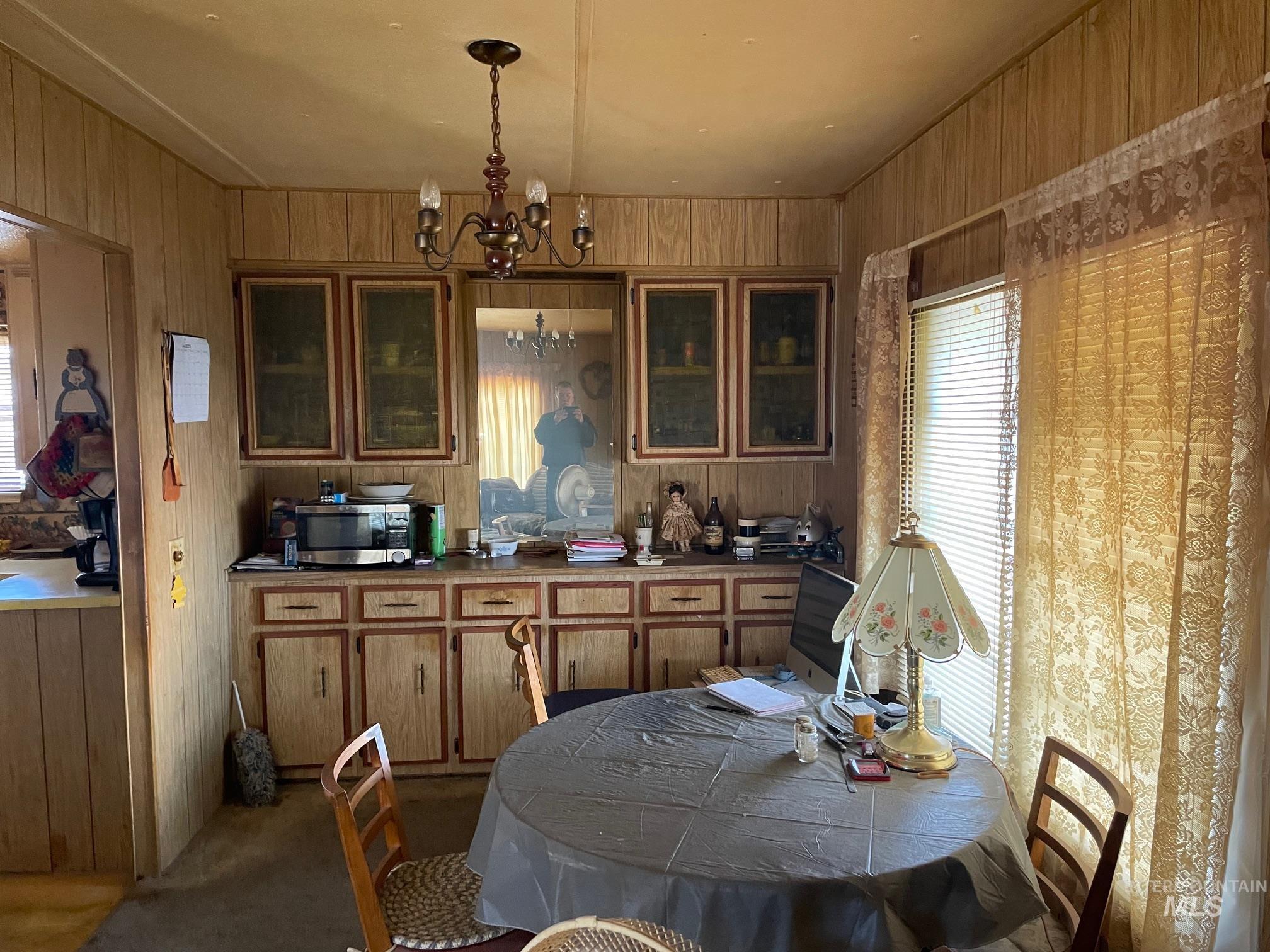 Dining area featuring a chandelier, wood walls, and dark colored carpet