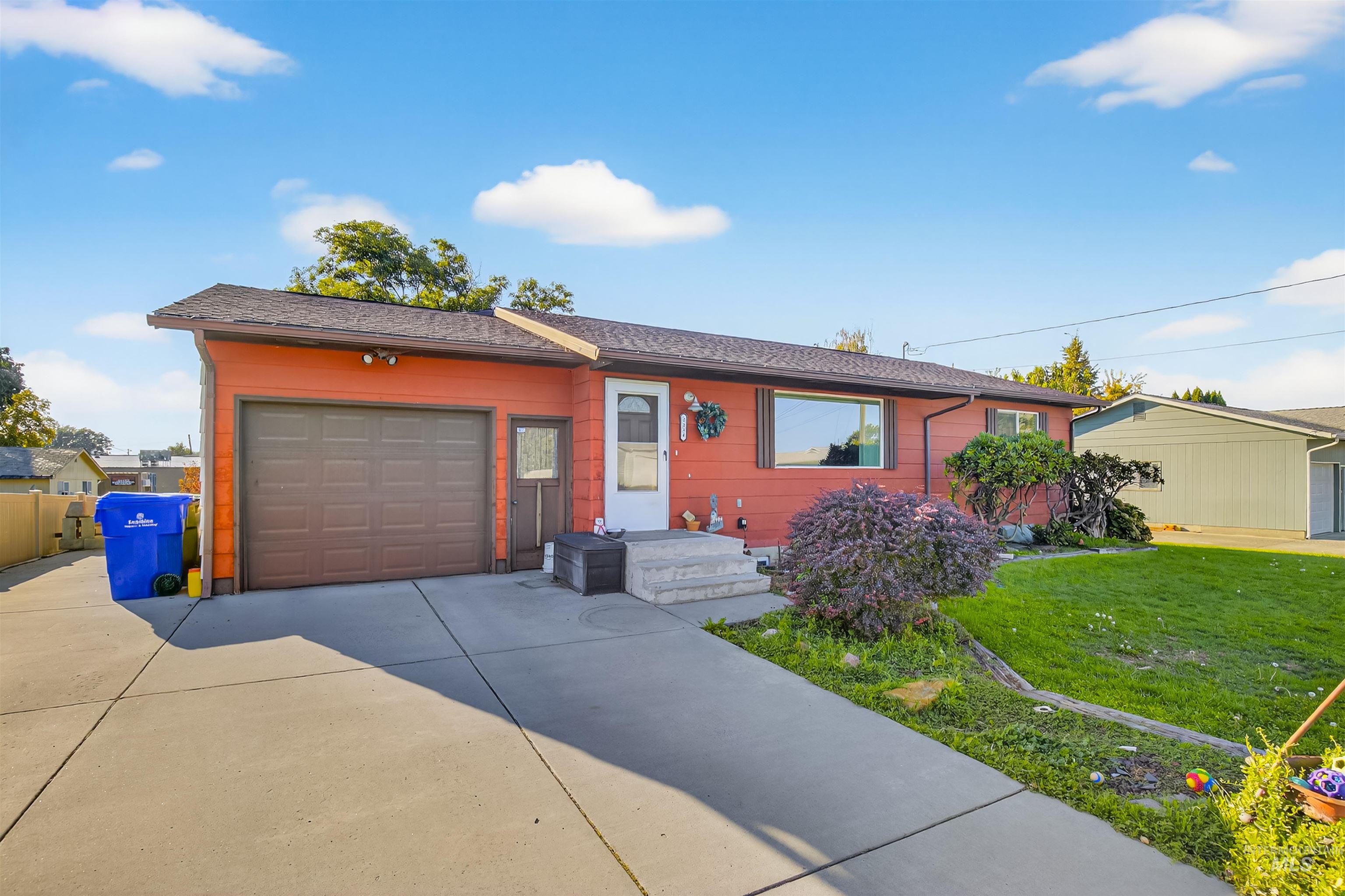 Ranch-style house with driveway, a front yard, an attached garage, and a shingled roof
