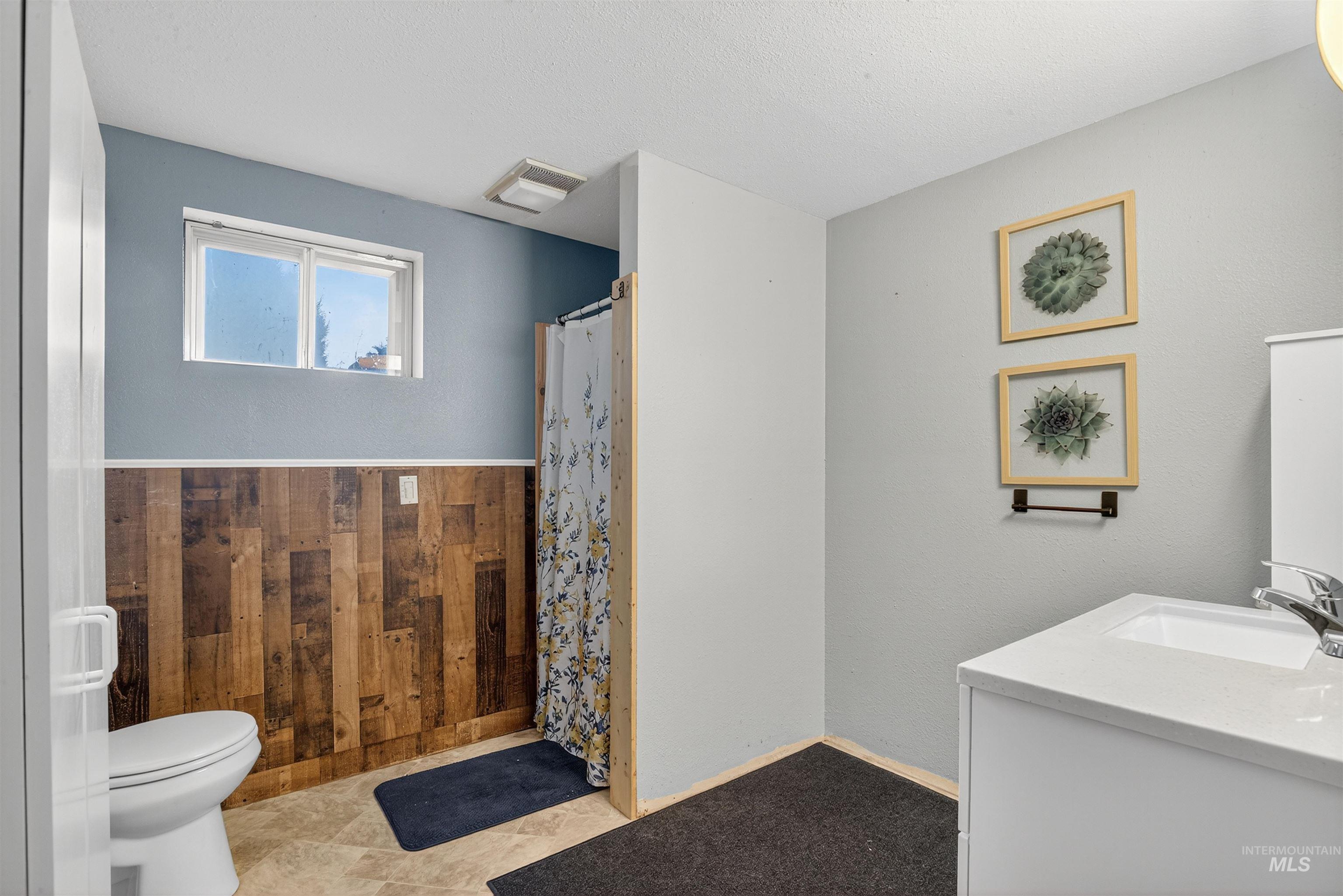 Bathroom with vanity, wood walls, and a shower with shower curtain