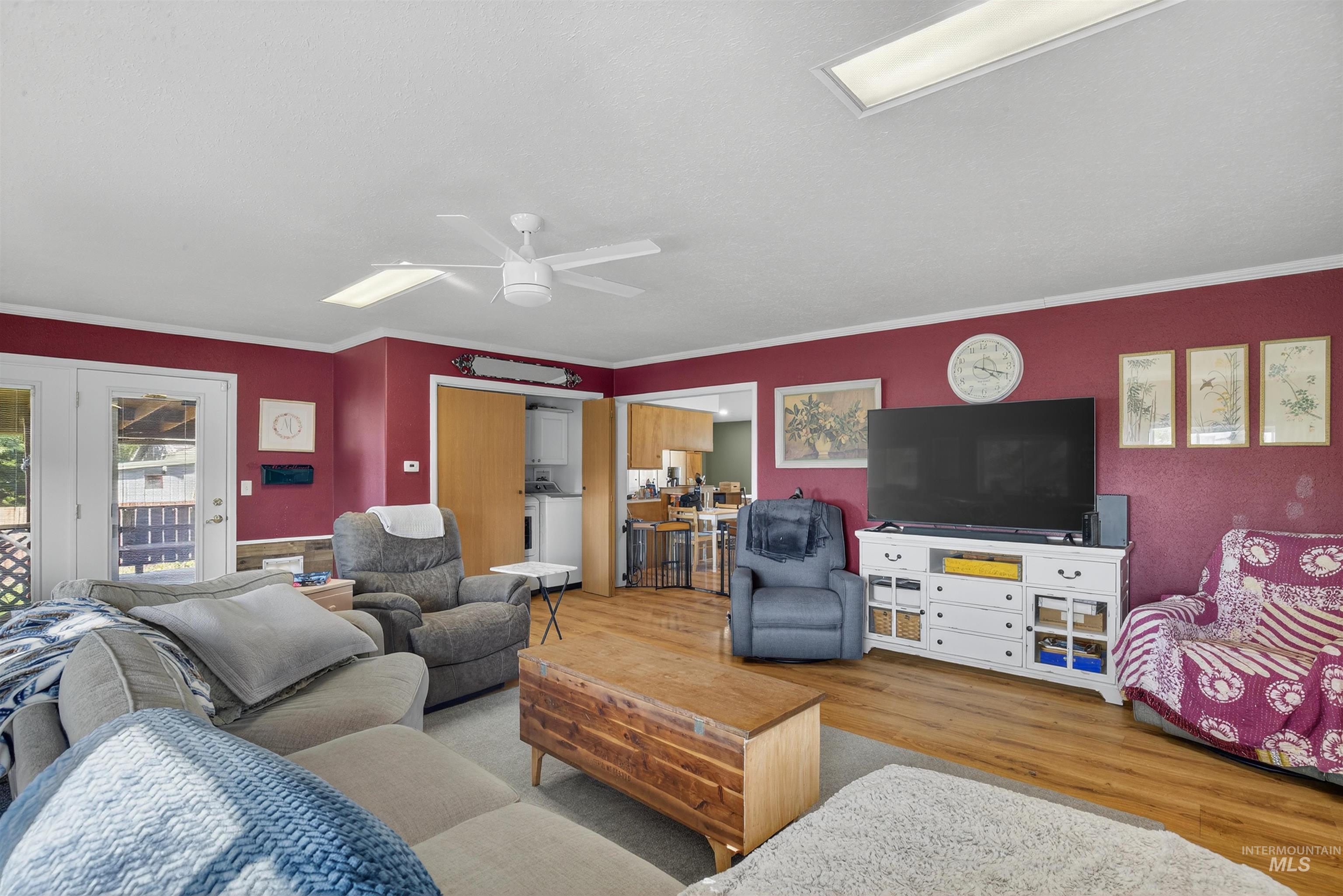 Living room featuring wood finished floors, crown molding, and ceiling fan