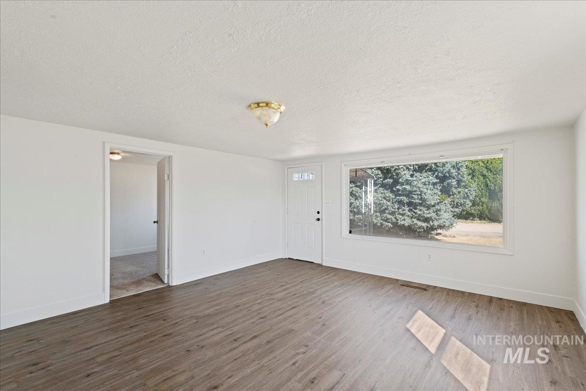 Unfurnished living room with wood finished floors and a textured ceiling