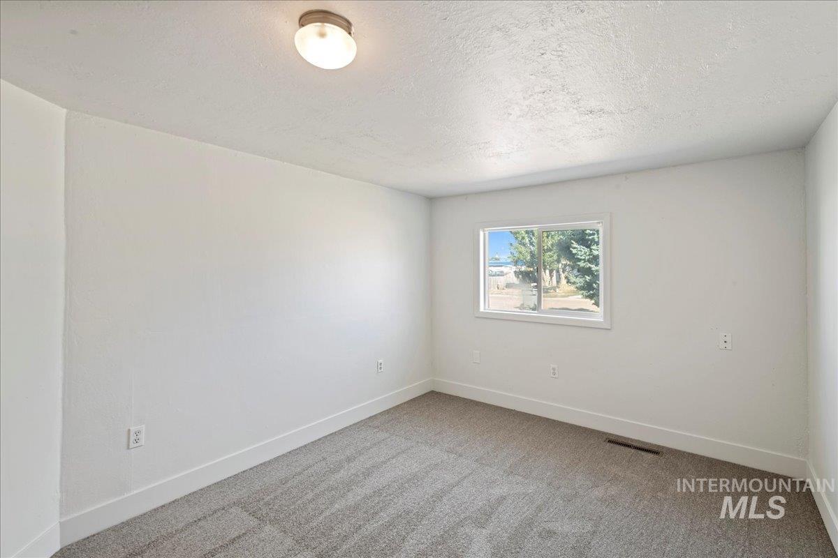 Carpeted empty room featuring baseboards and a textured ceiling