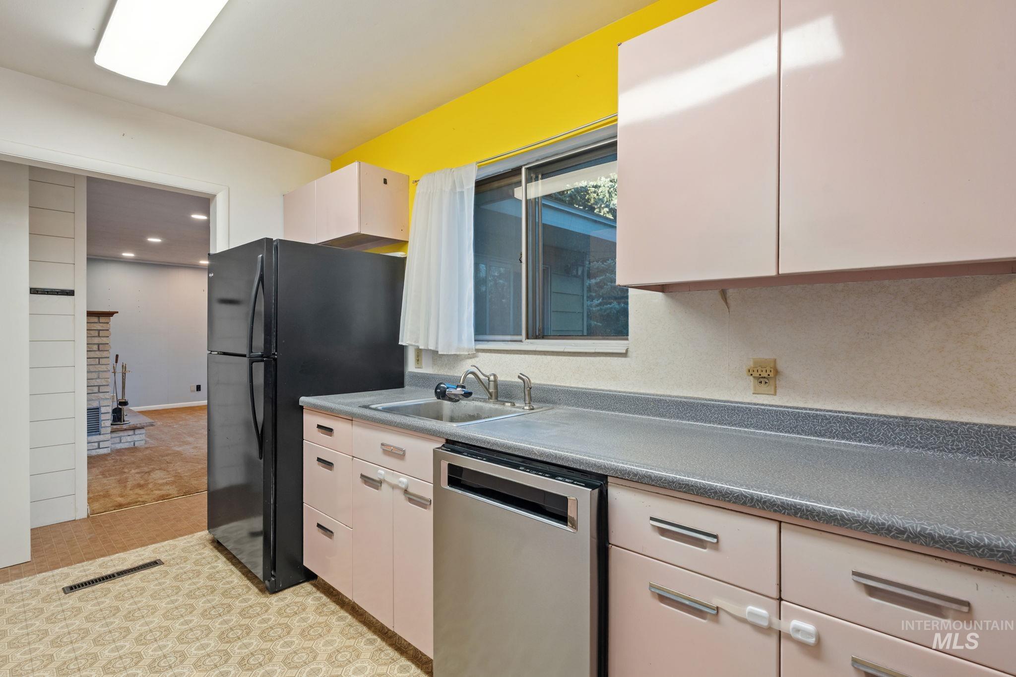 Kitchen featuring dishwasher, freestanding refrigerator, and white cabinets
