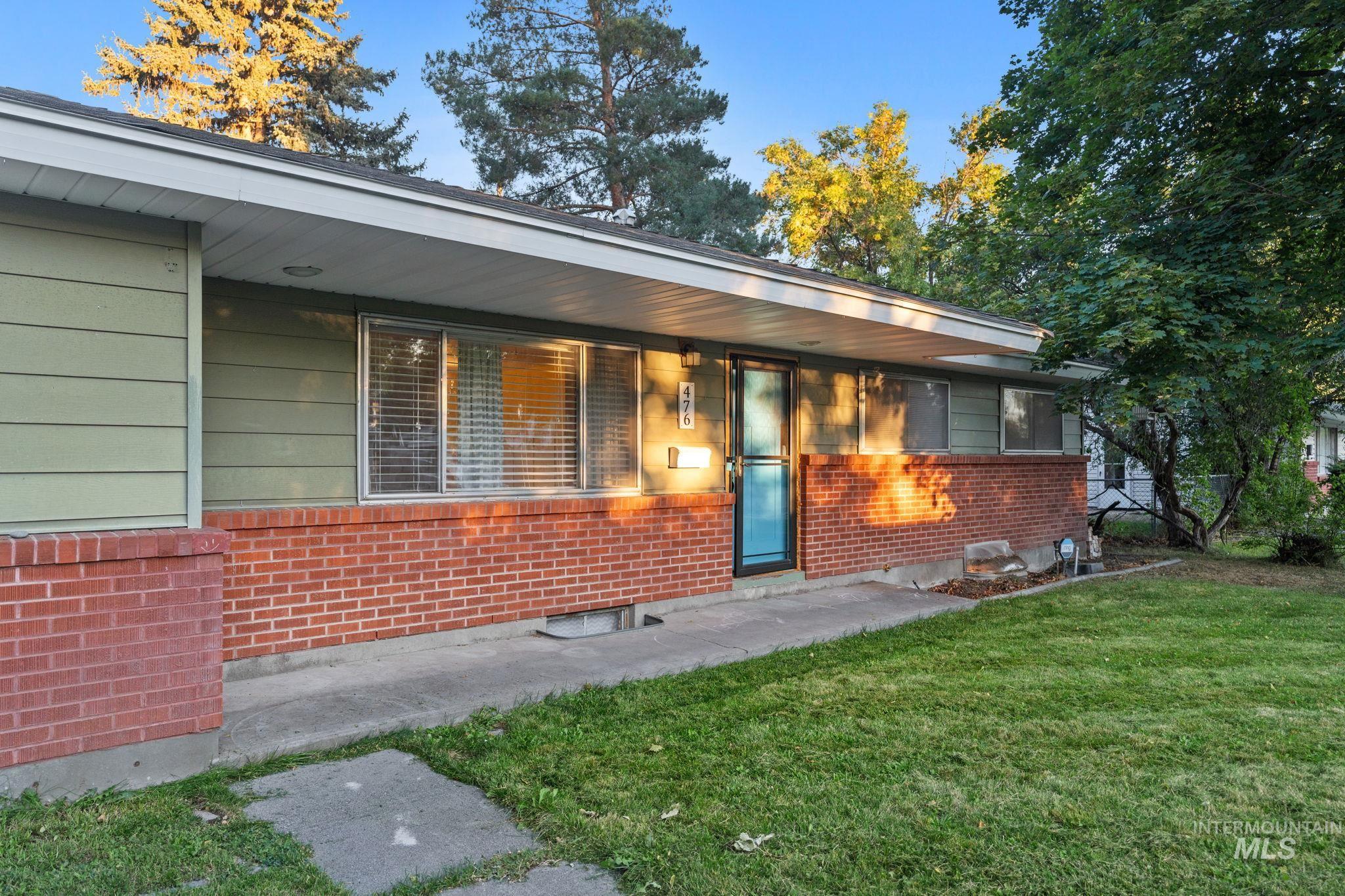 Doorway to property featuring a yard and brick siding