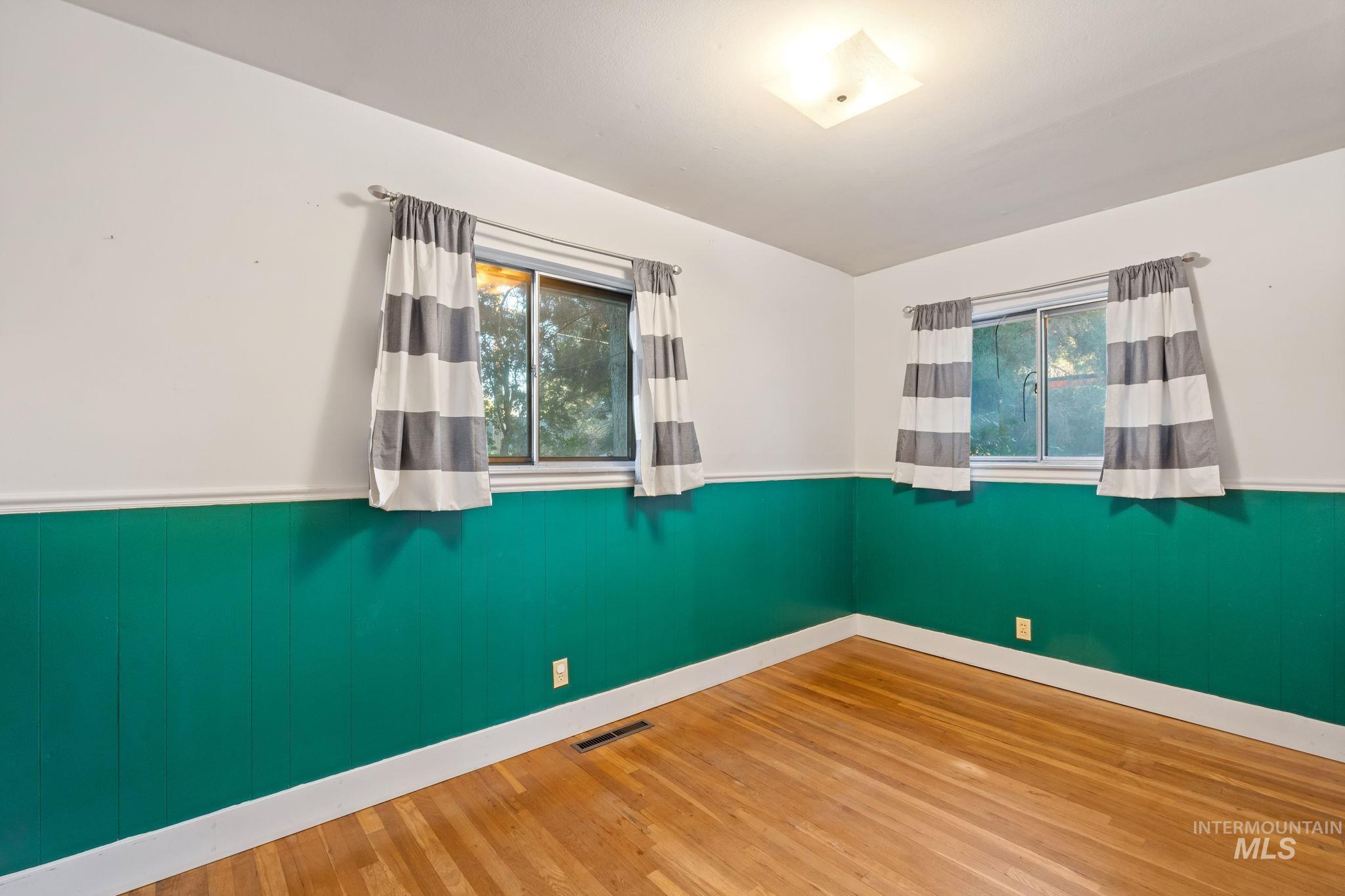 Spare room with a wainscoted wall, wood finished floors, and wood walls