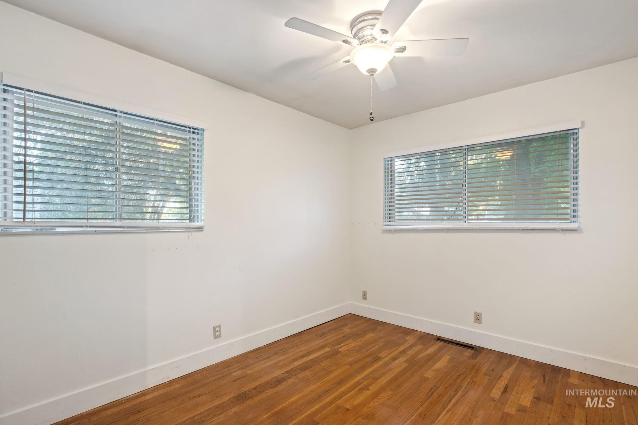 Empty room featuring wood finished floors and a ceiling fan