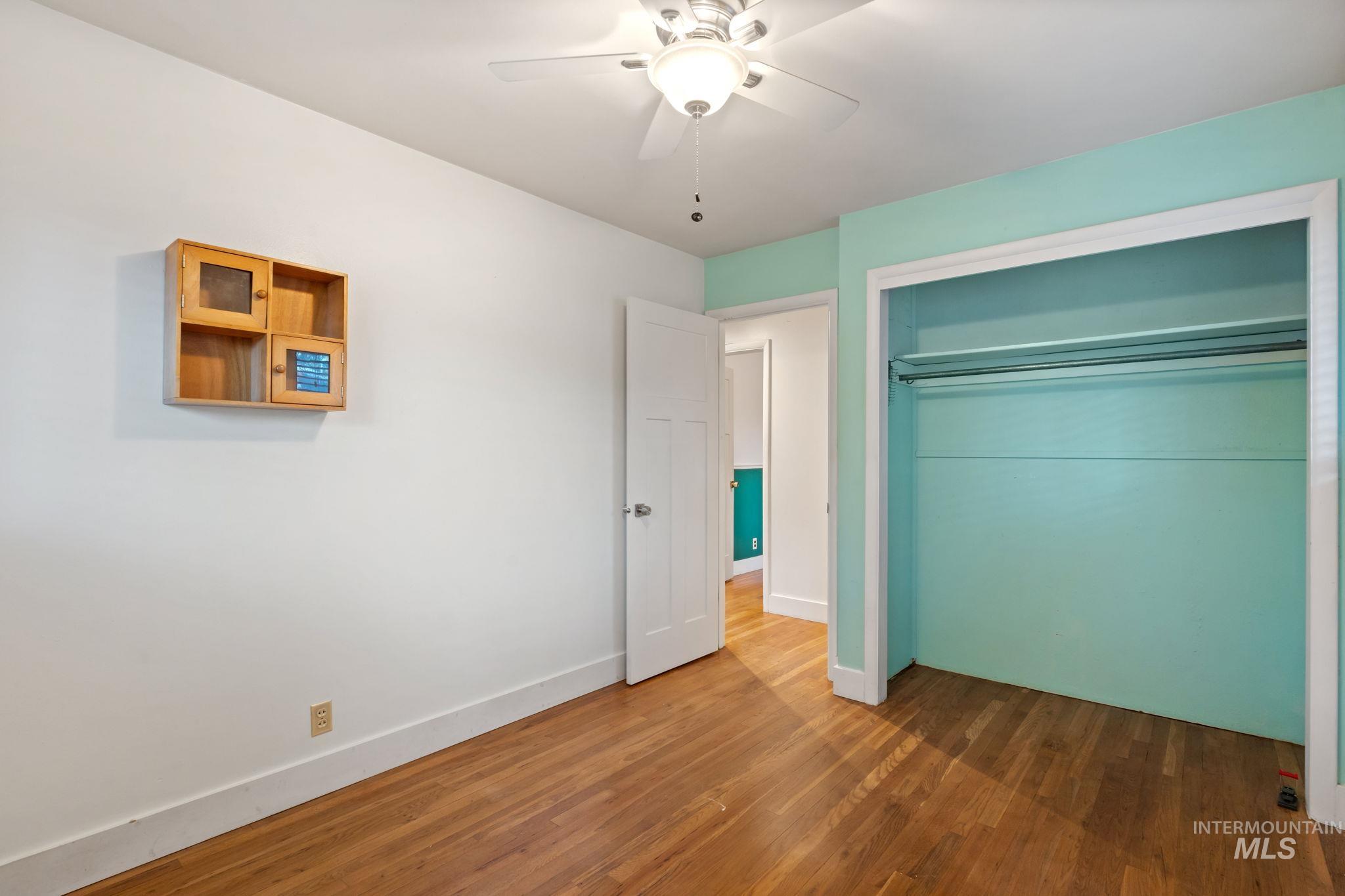Unfurnished bedroom featuring wood finished floors, ceiling fan, and a closet