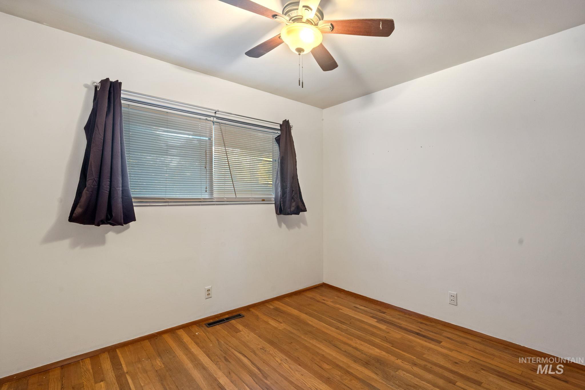 Spare room with wood finished floors and ceiling fan
