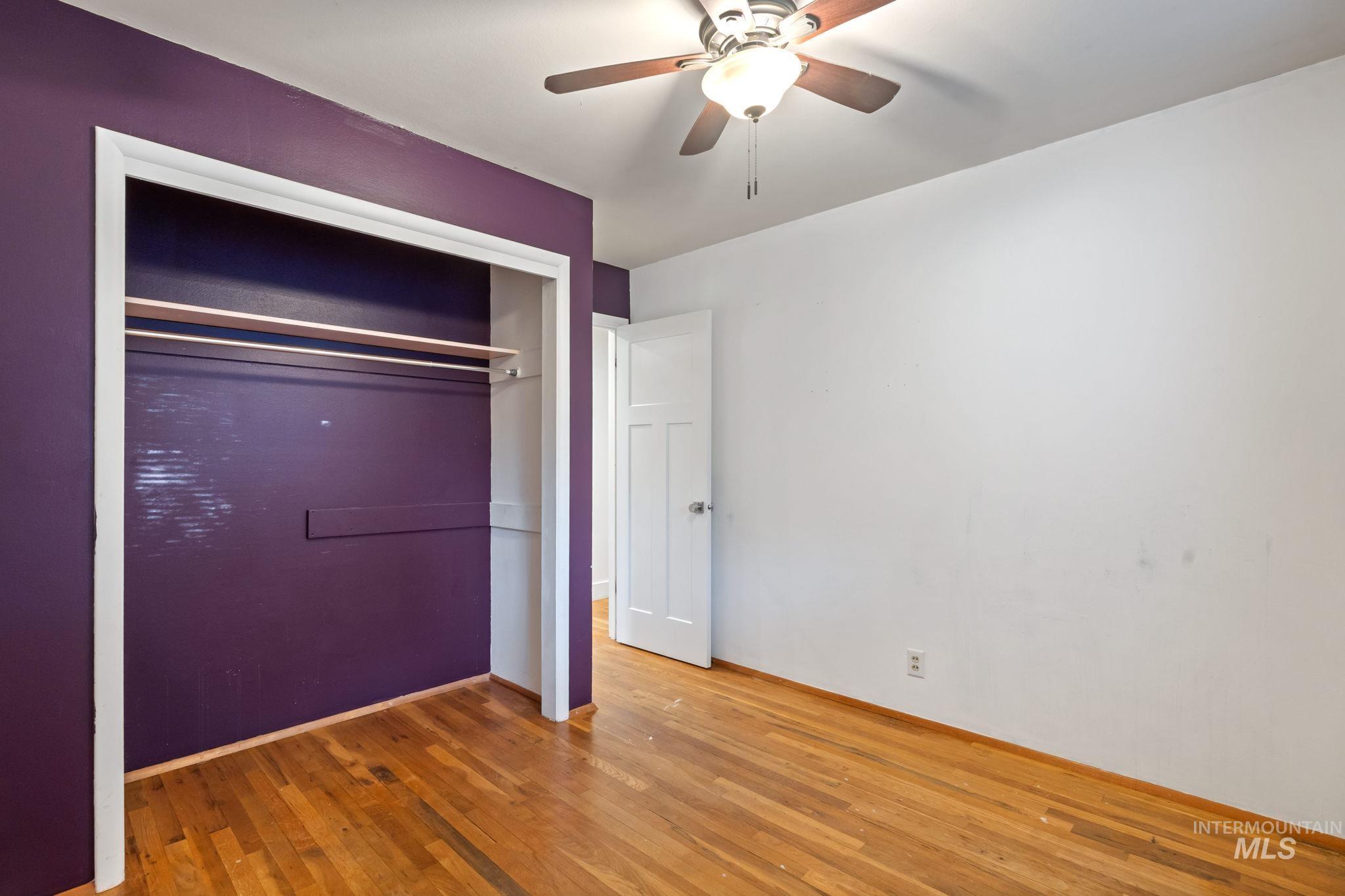 Unfurnished bedroom featuring wood-type flooring, a closet, and ceiling fan