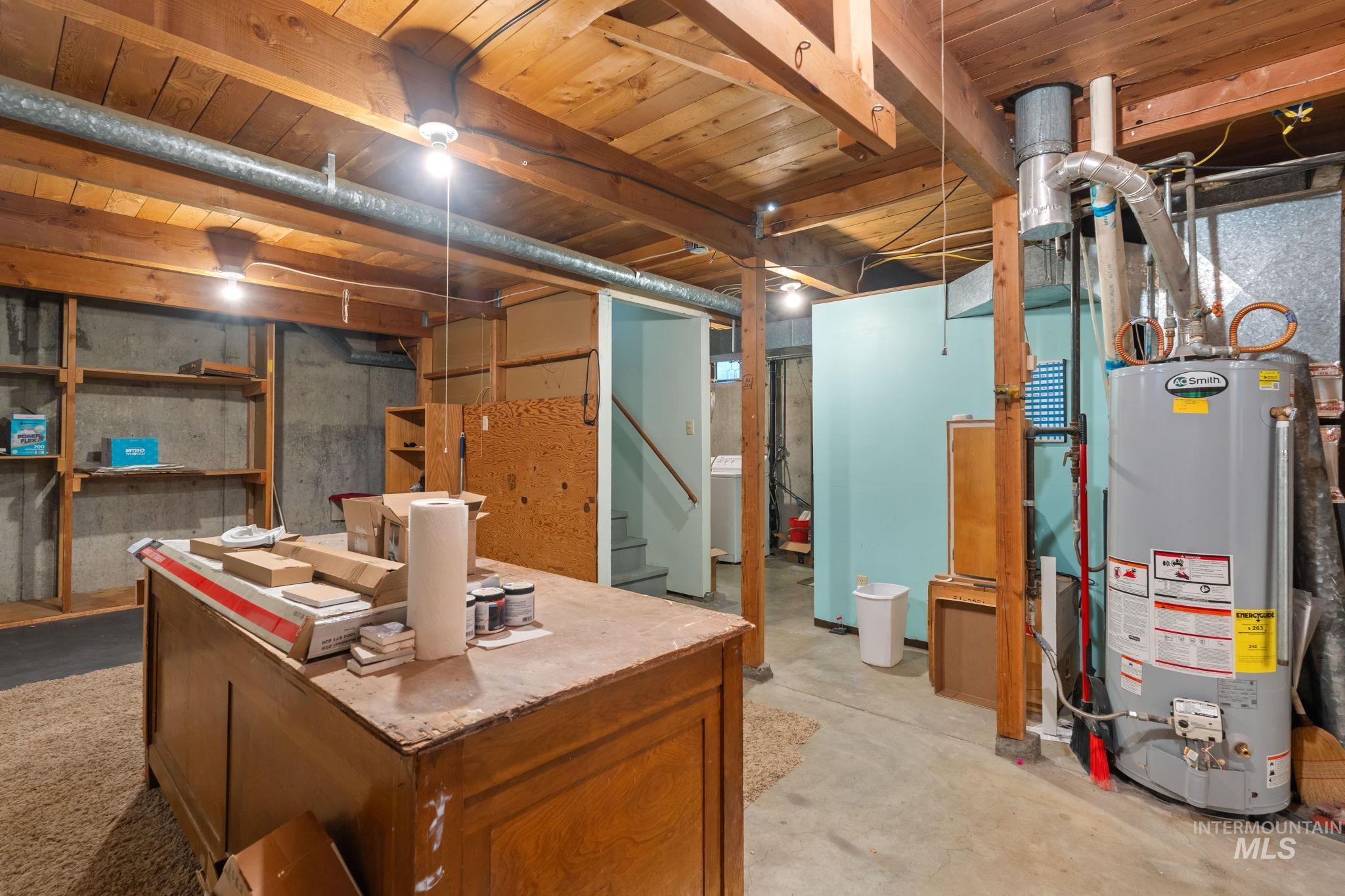 Unfinished basement with gas water heater, stairs, and washer / clothes dryer