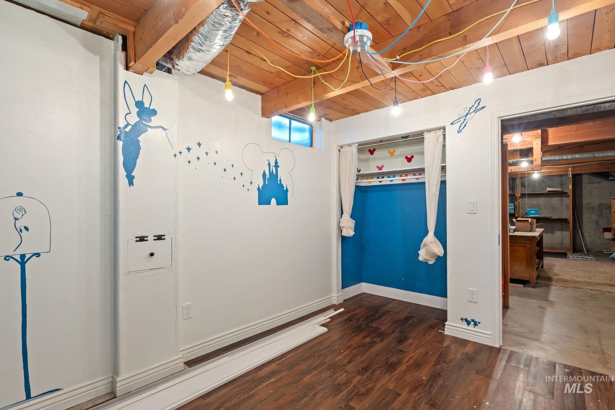 Unfurnished bedroom with a wooden ceiling with exposed beams and dark wood-style floors