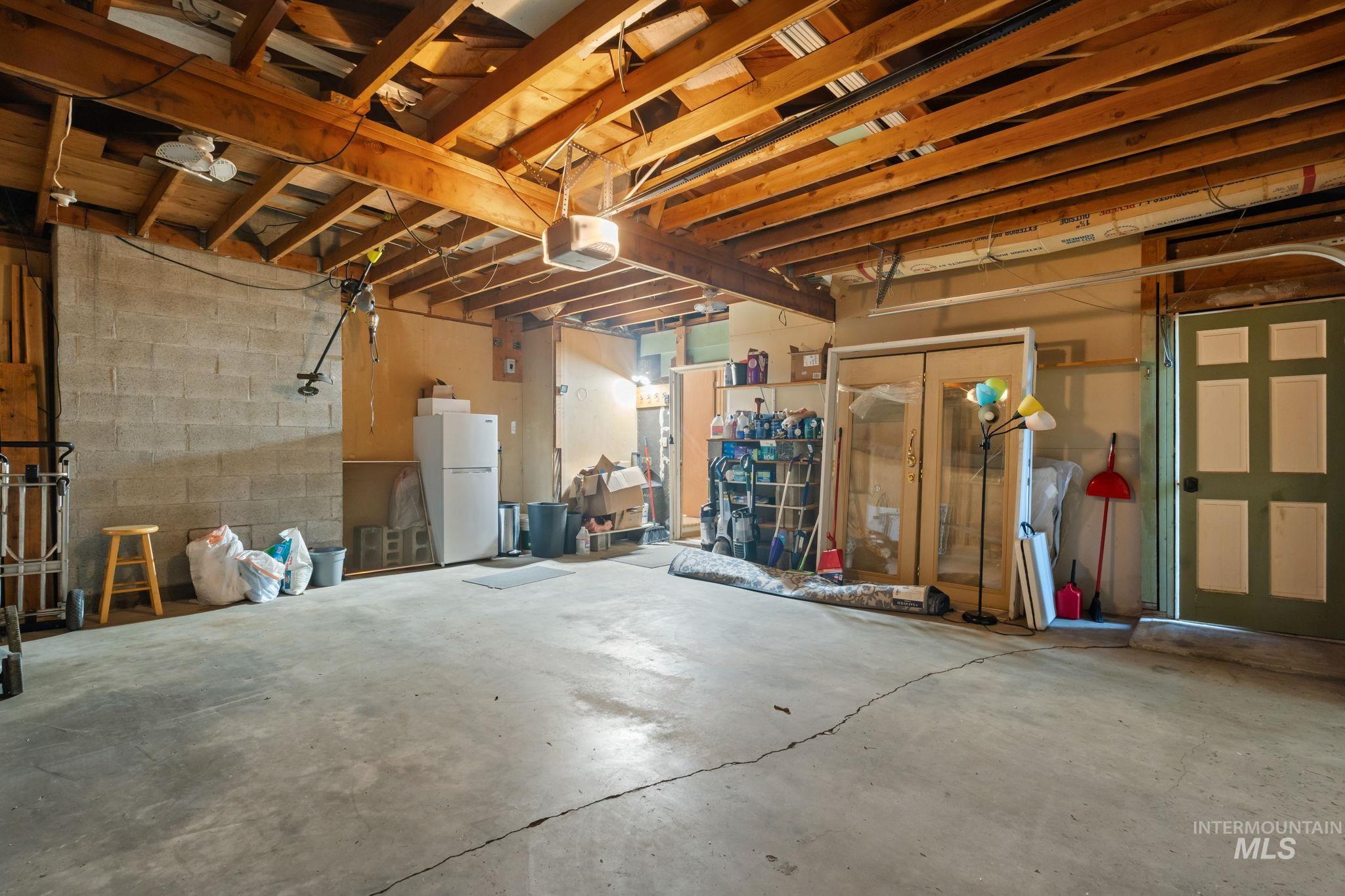 Garage with concrete block wall, freestanding refrigerator, and a garage door opener
