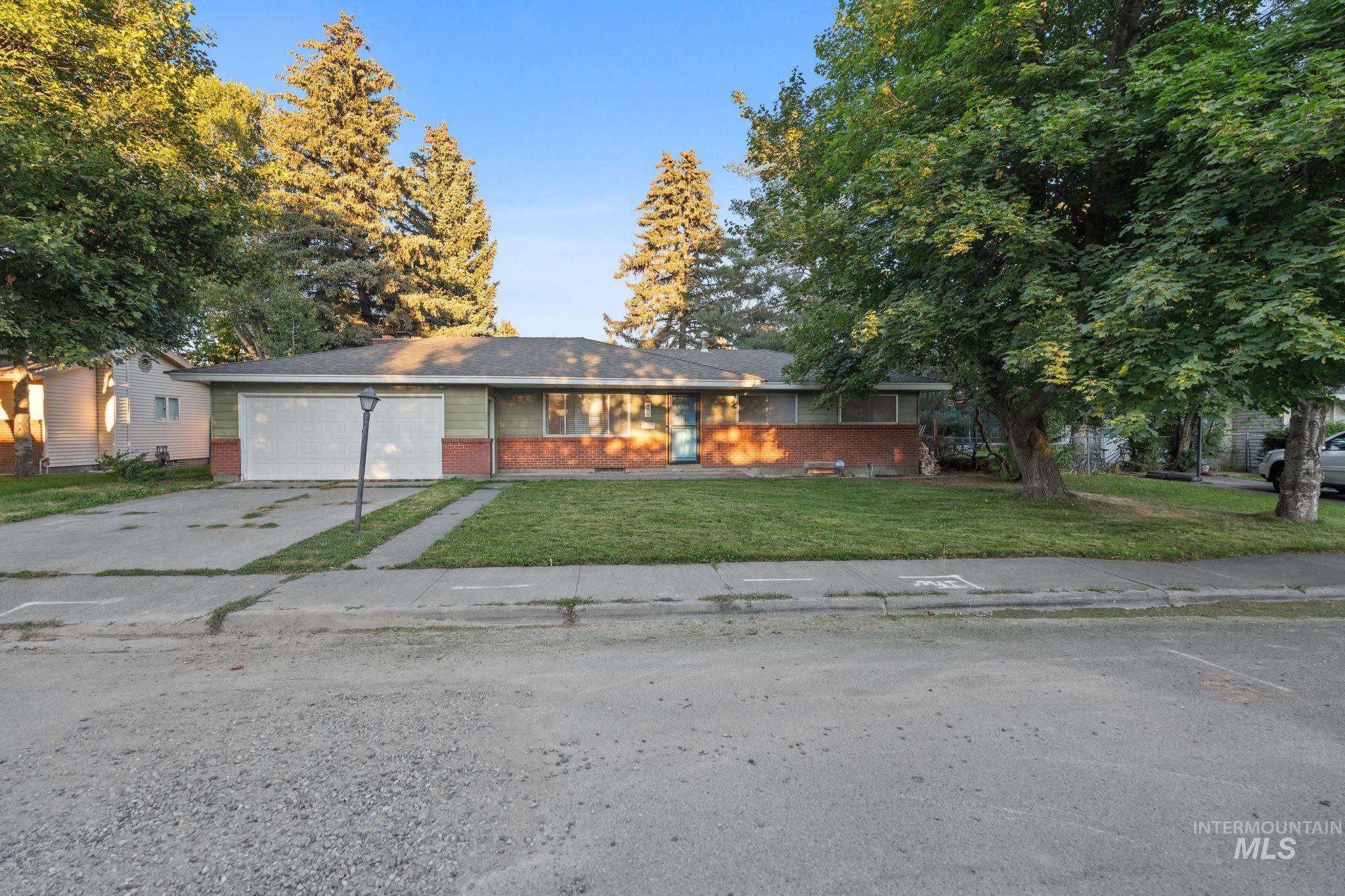 Single story home with brick siding, driveway, a front yard, and a garage