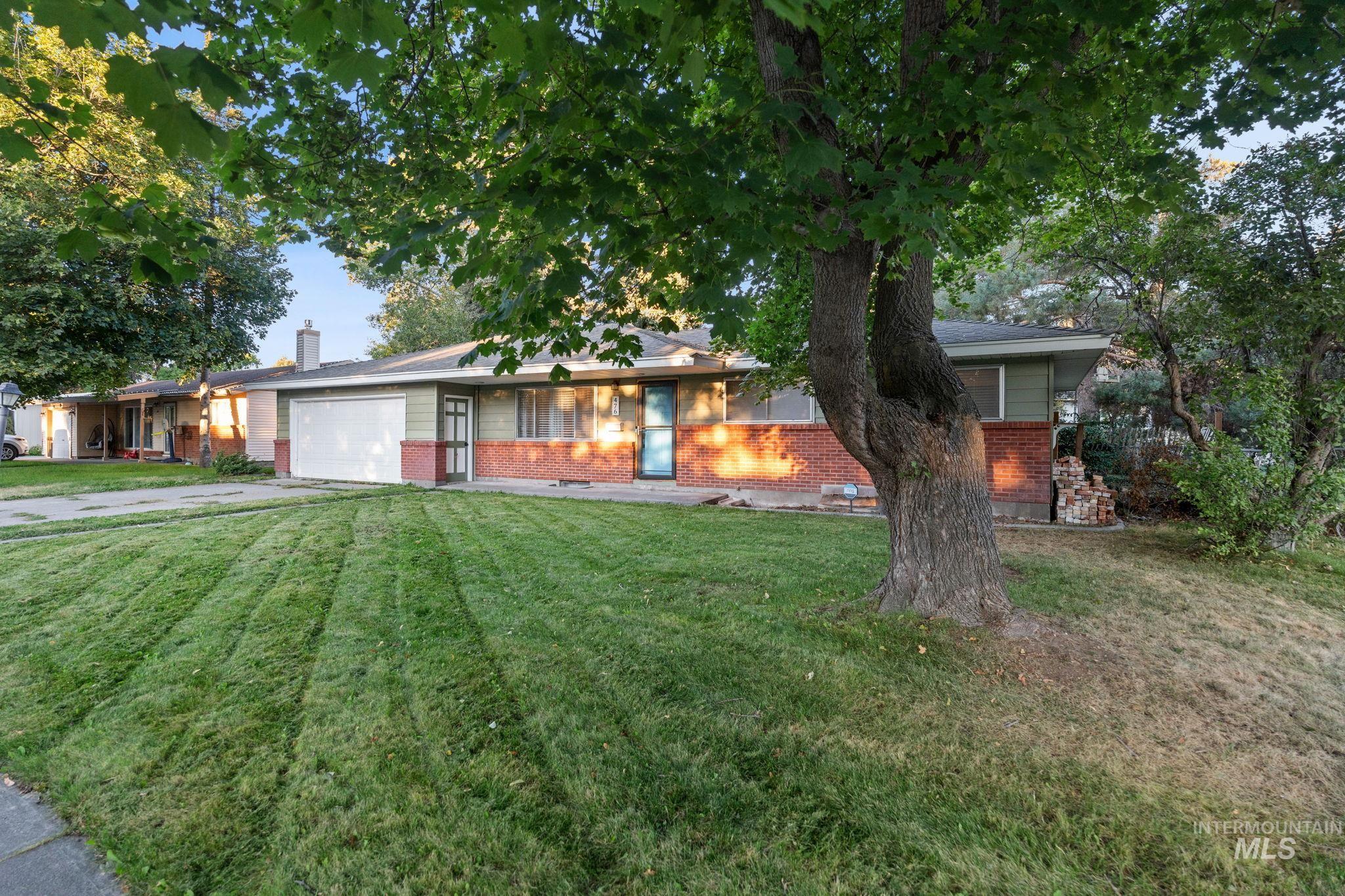 Ranch-style house featuring brick siding, an attached garage, a front yard, and driveway