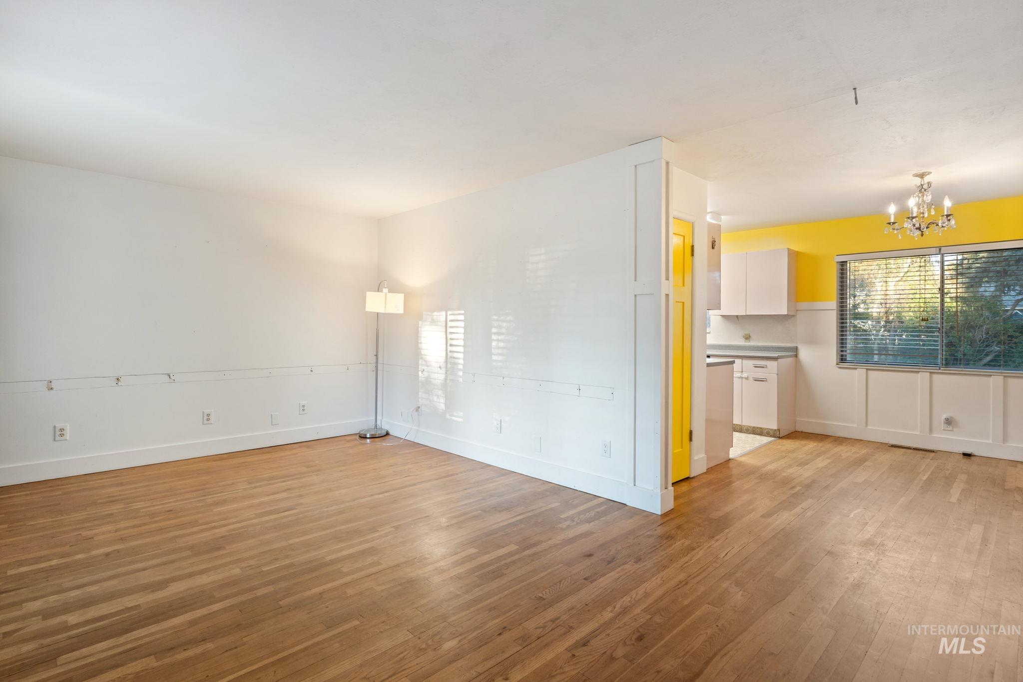 Empty room featuring light wood finished floors and a chandelier