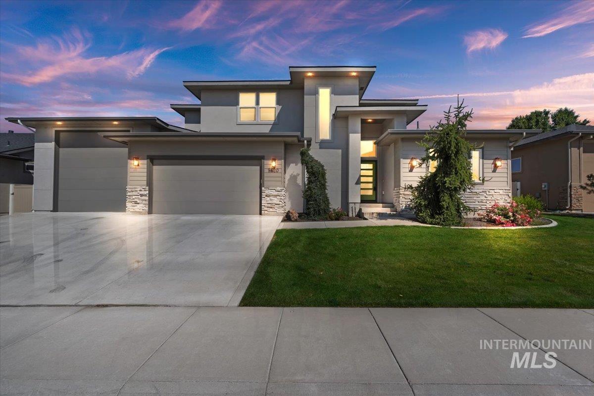 Prairie-style house featuring stone siding, concrete driveway, a front lawn, stucco siding, and a garage