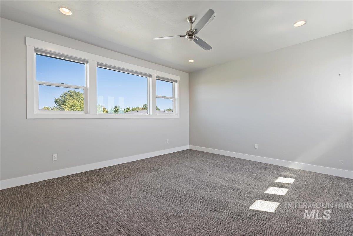 Spare room featuring dark colored carpet, recessed lighting, and ceiling fan
