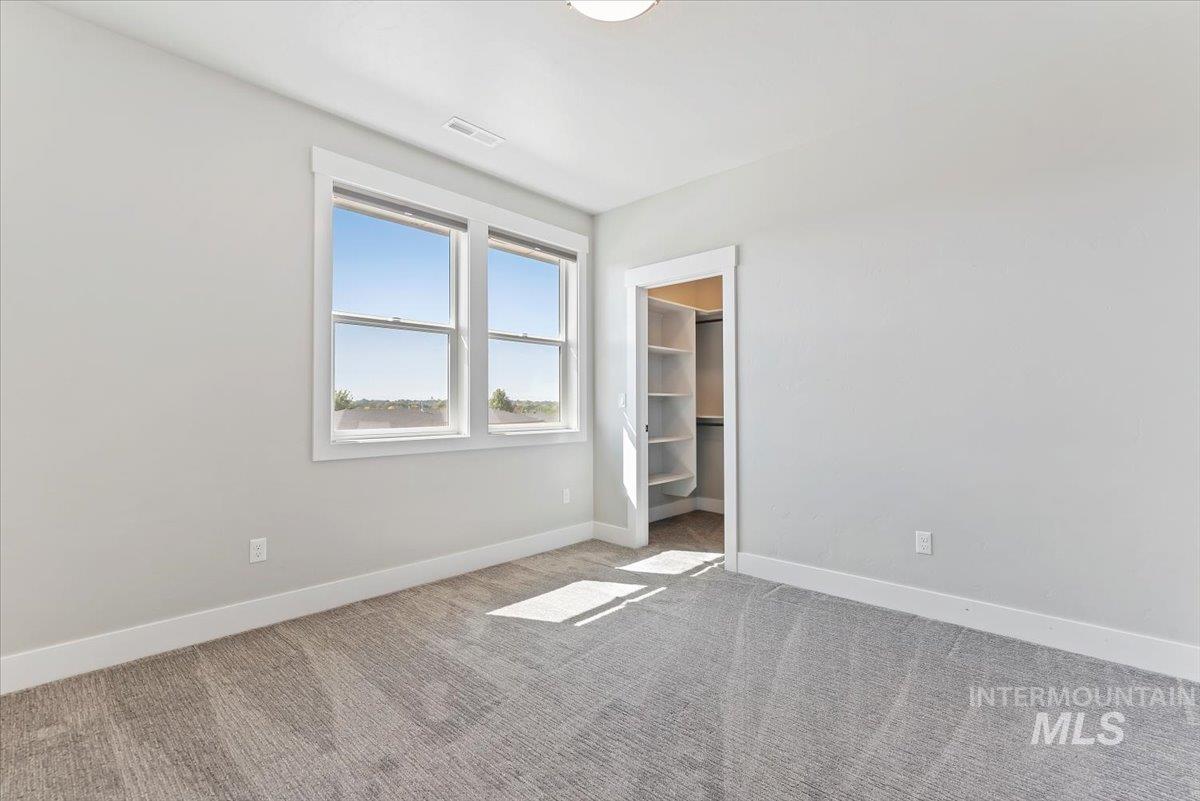 Unfurnished bedroom with carpet and a spacious closet