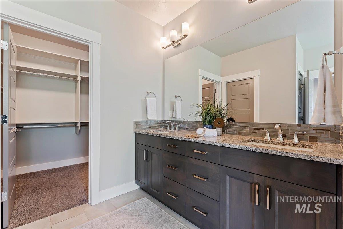 Full bathroom featuring double vanity, light tile patterned floors, and a spacious closet