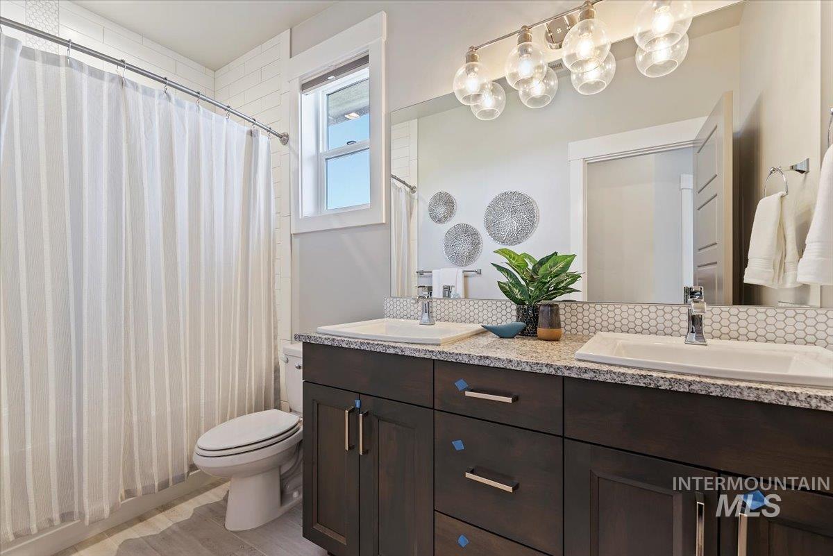 Full bathroom with double vanity and a shower with shower curtain