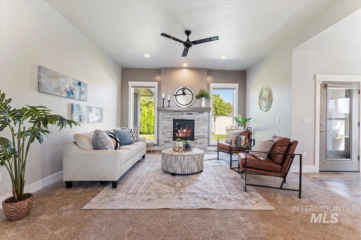 Living area featuring a stone fireplace, recessed lighting, and ceiling fan