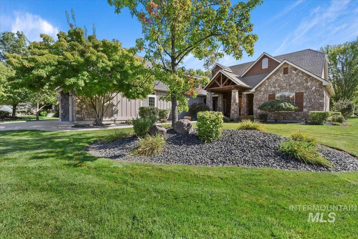 Craftsman-style house featuring stone siding, a front lawn, driveway, and a garage