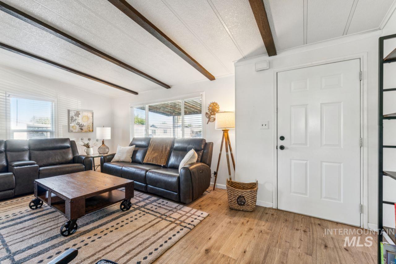 Living room featuring beamed ceiling, light wood-style flooring, and a textured ceiling