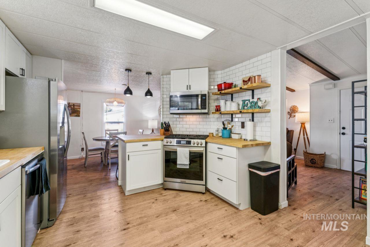 Kitchen featuring stainless steel appliances, white cabinets, light wood-style flooring, and butcher block countertops