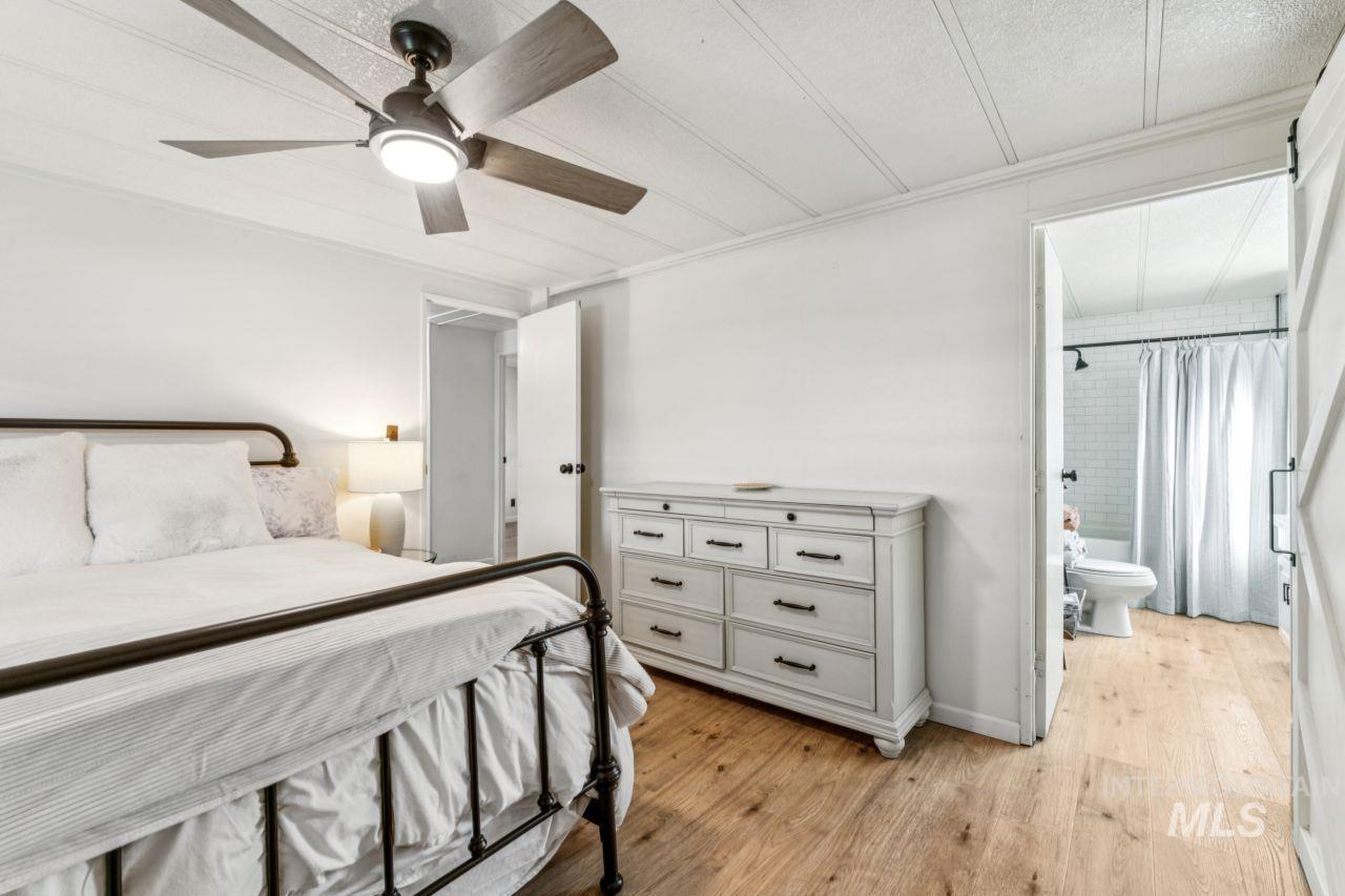 Bedroom with light wood-type flooring, a ceiling fan, ornamental molding, and ensuite bath