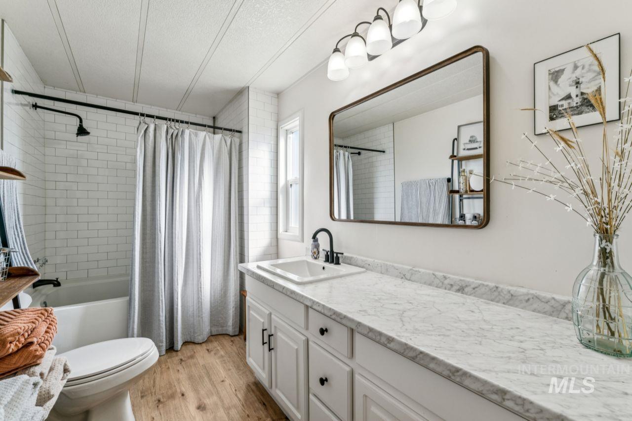 Bathroom featuring shower / tub combo, vanity, light wood-style flooring, and a textured ceiling