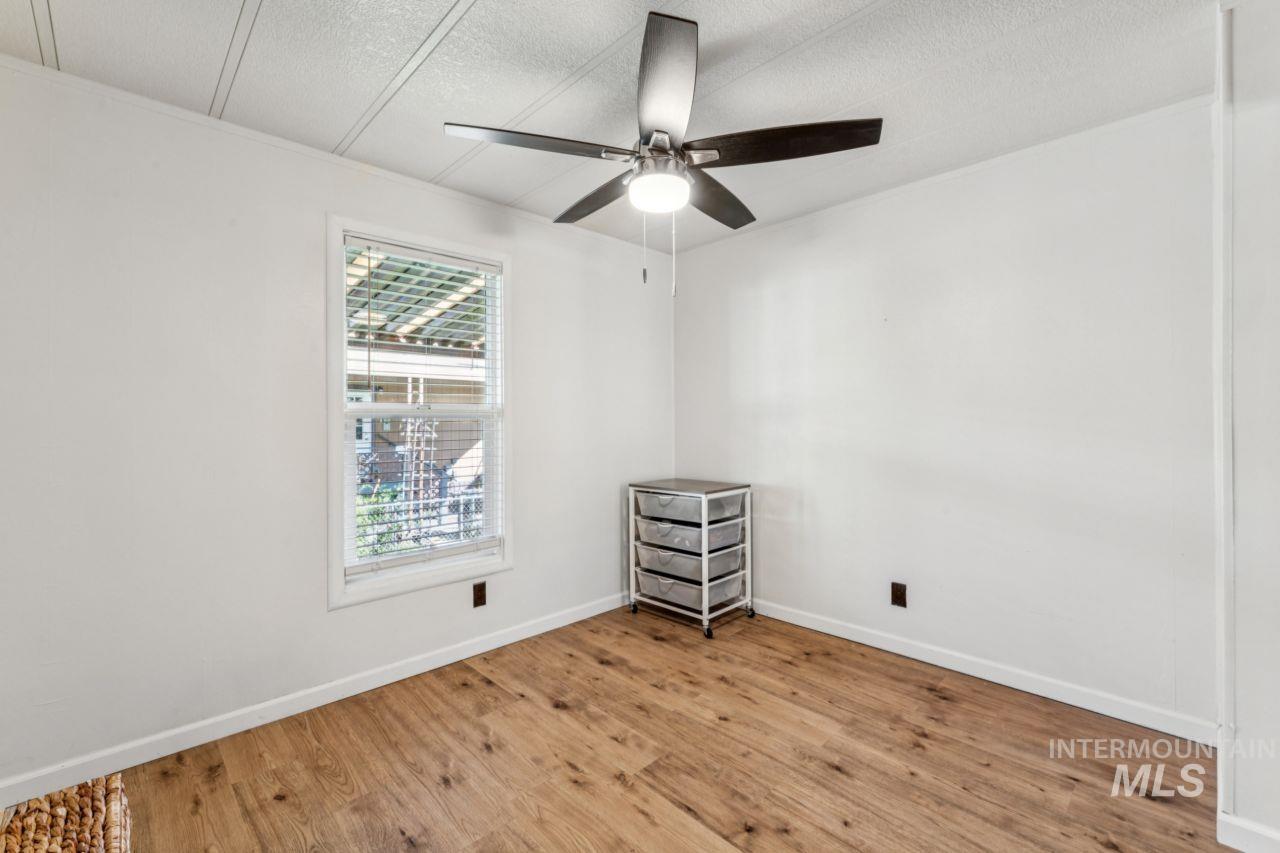 Spare room featuring wood finished floors, a ceiling fan, and a textured ceiling