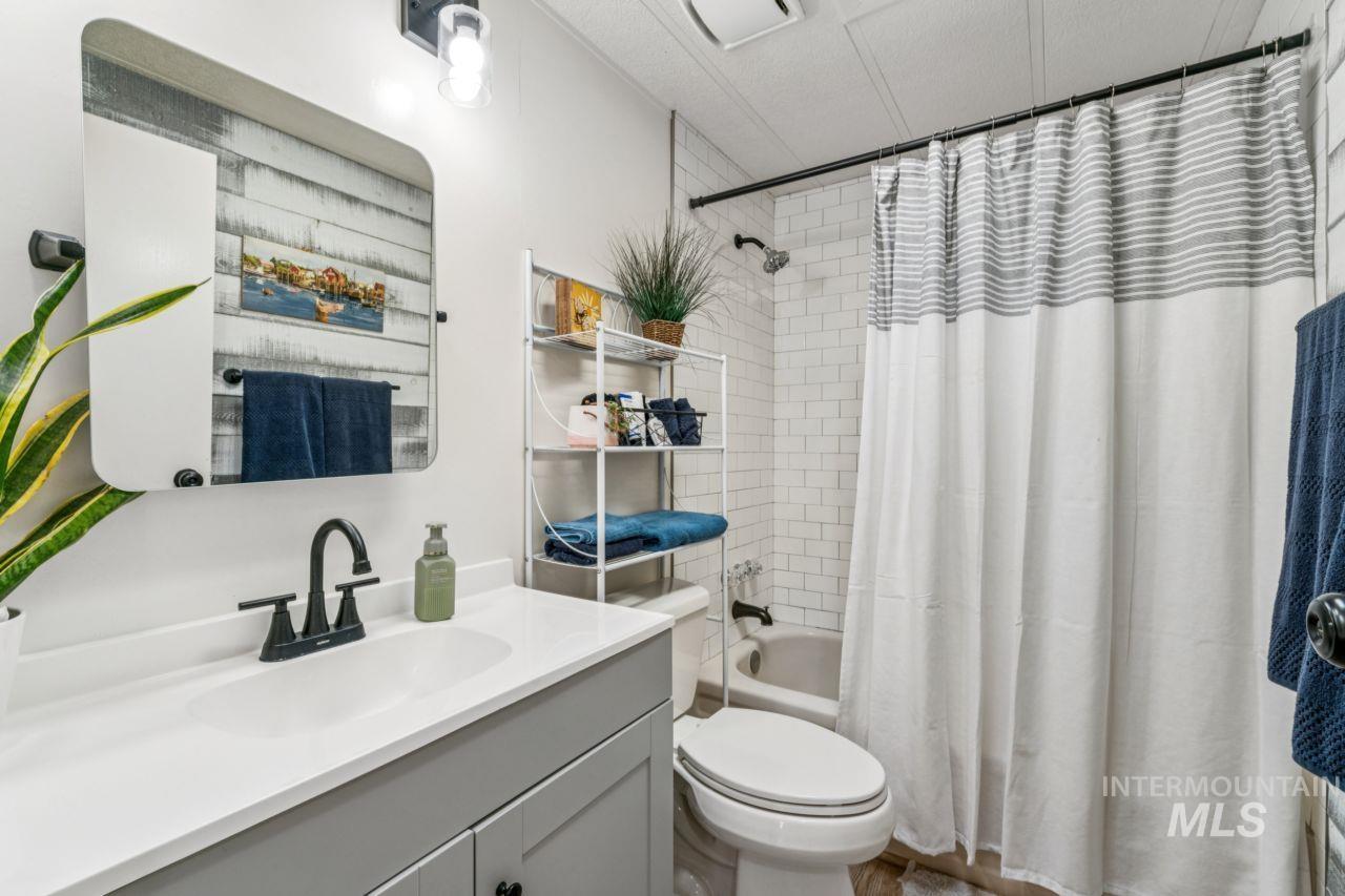 Bathroom featuring vanity and shower / bathtub combination with curtain