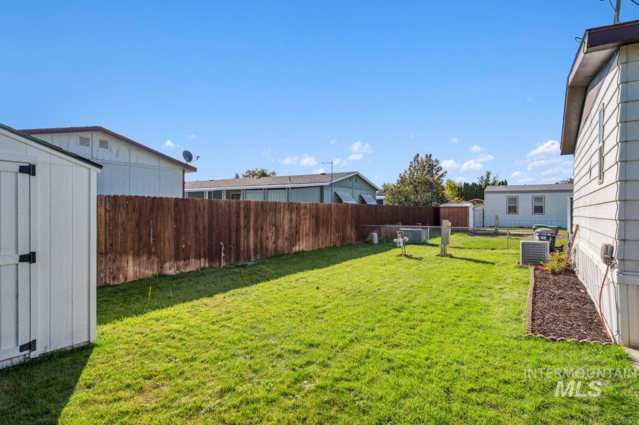Fenced backyard featuring a shed
