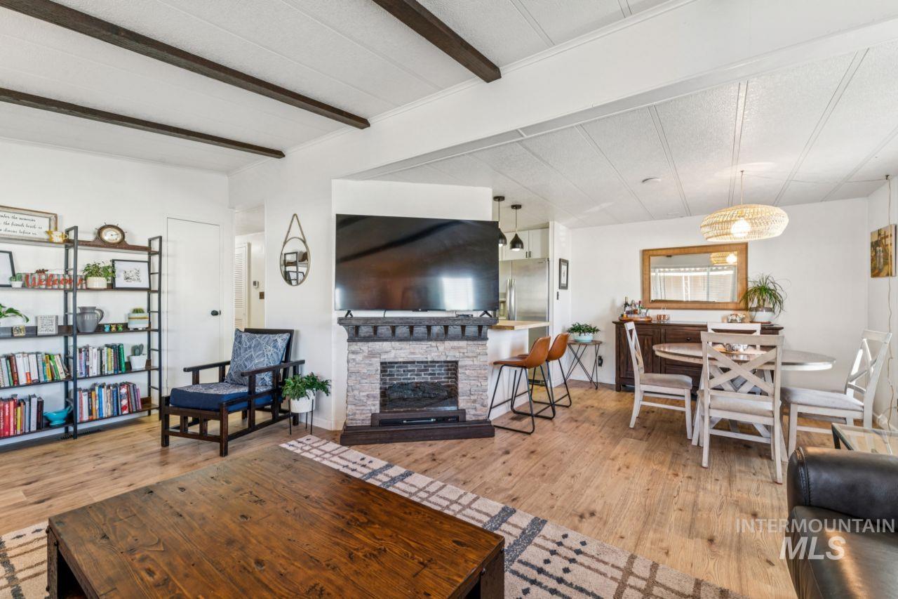 Living room with light wood-style floors, a fireplace, and beam ceiling