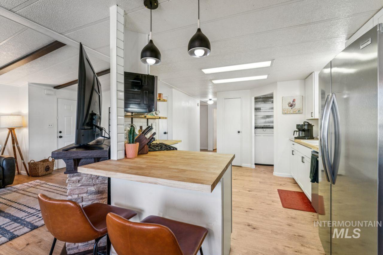 Kitchen featuring wood counters, freestanding refrigerator, white cabinetry, and a breakfast bar area