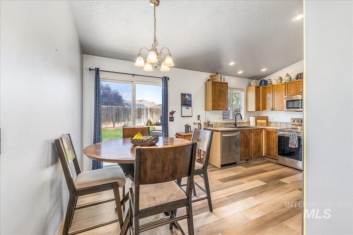 Open to the kitchen, the dining area is flooded with natural light and features light wood-style flooring, a chandelier, and recessed lighting!