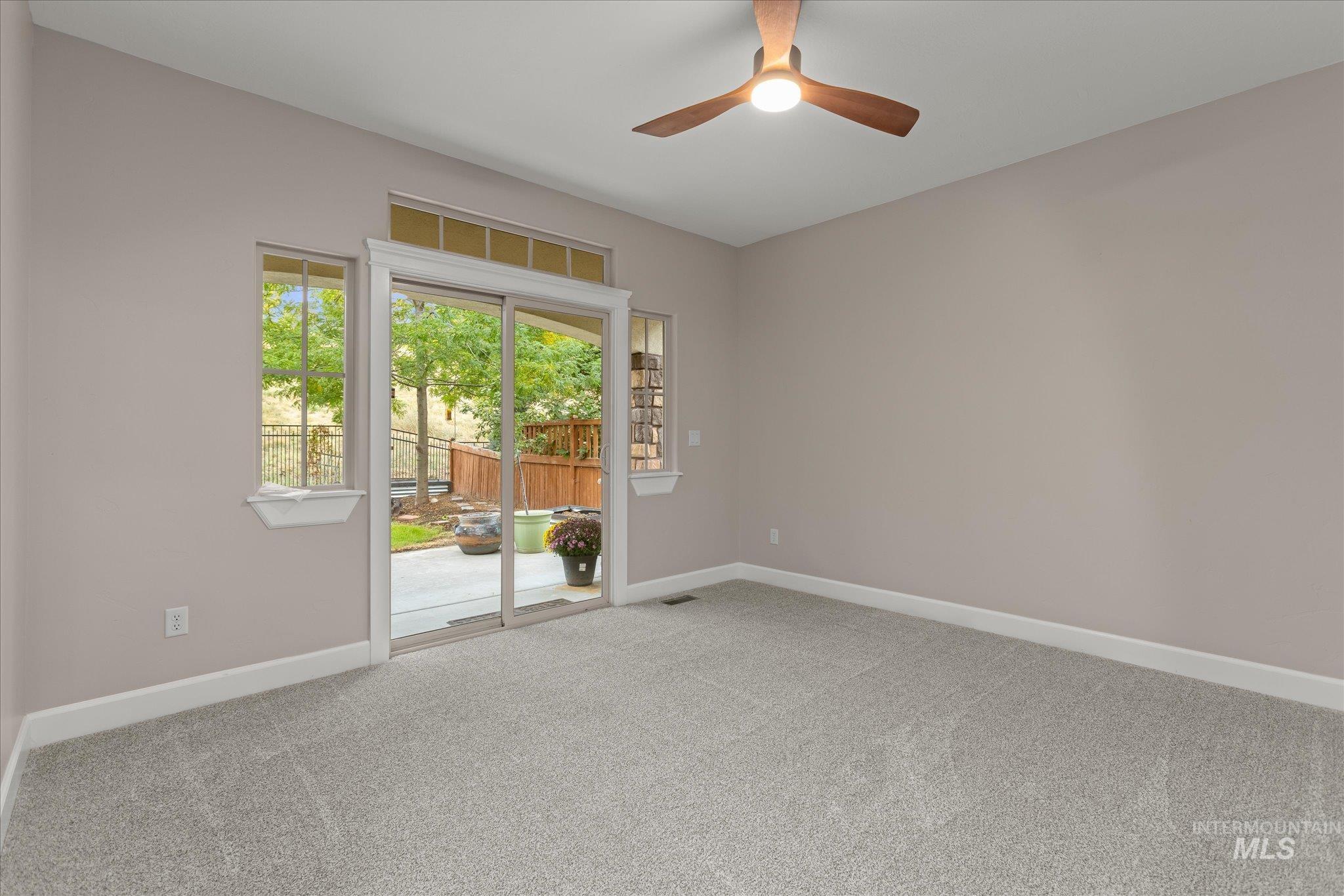 Empty room featuring carpet flooring and a ceiling fan