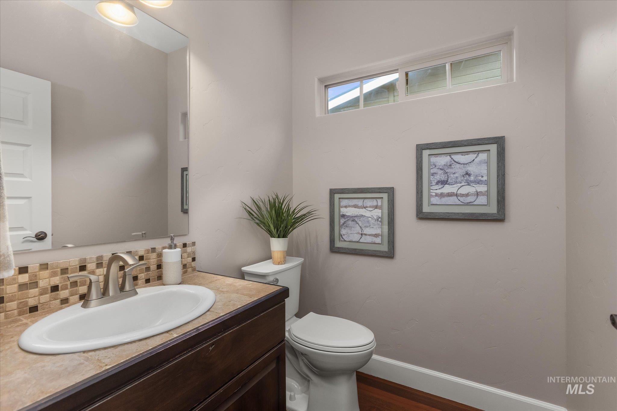 Bathroom featuring vanity, decorative backsplash, and dark wood-style flooring