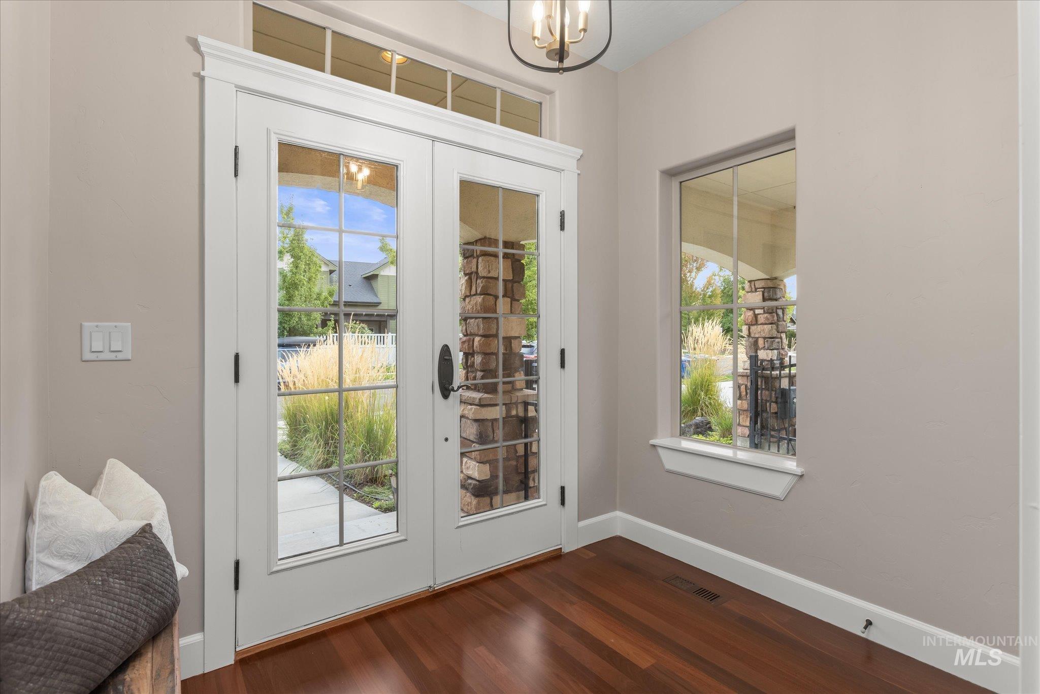 Entryway with wood finished floors, french doors, and a chandelier
