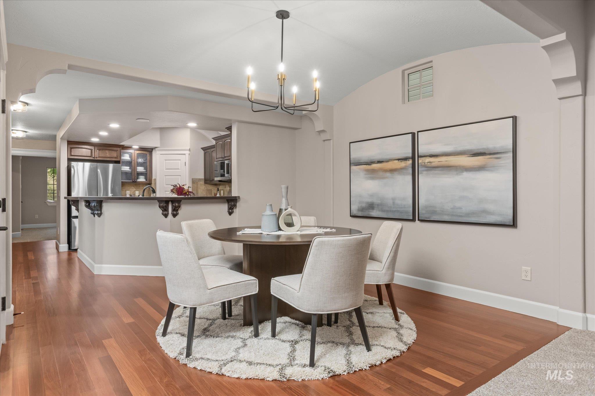 Dining room with vaulted ceiling, dark wood-style flooring, a chandelier, arched walkways, and recessed lighting