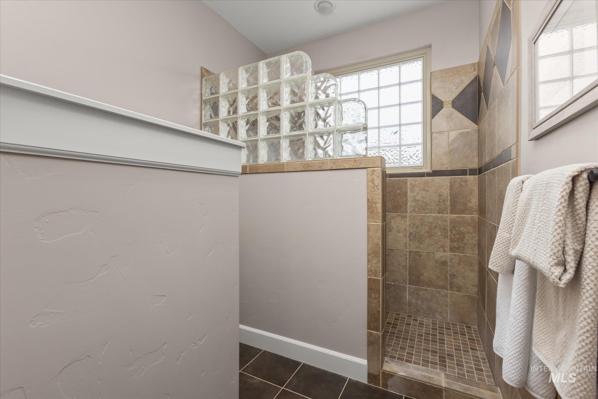 Full bathroom featuring a walk in shower and dark tile patterned flooring