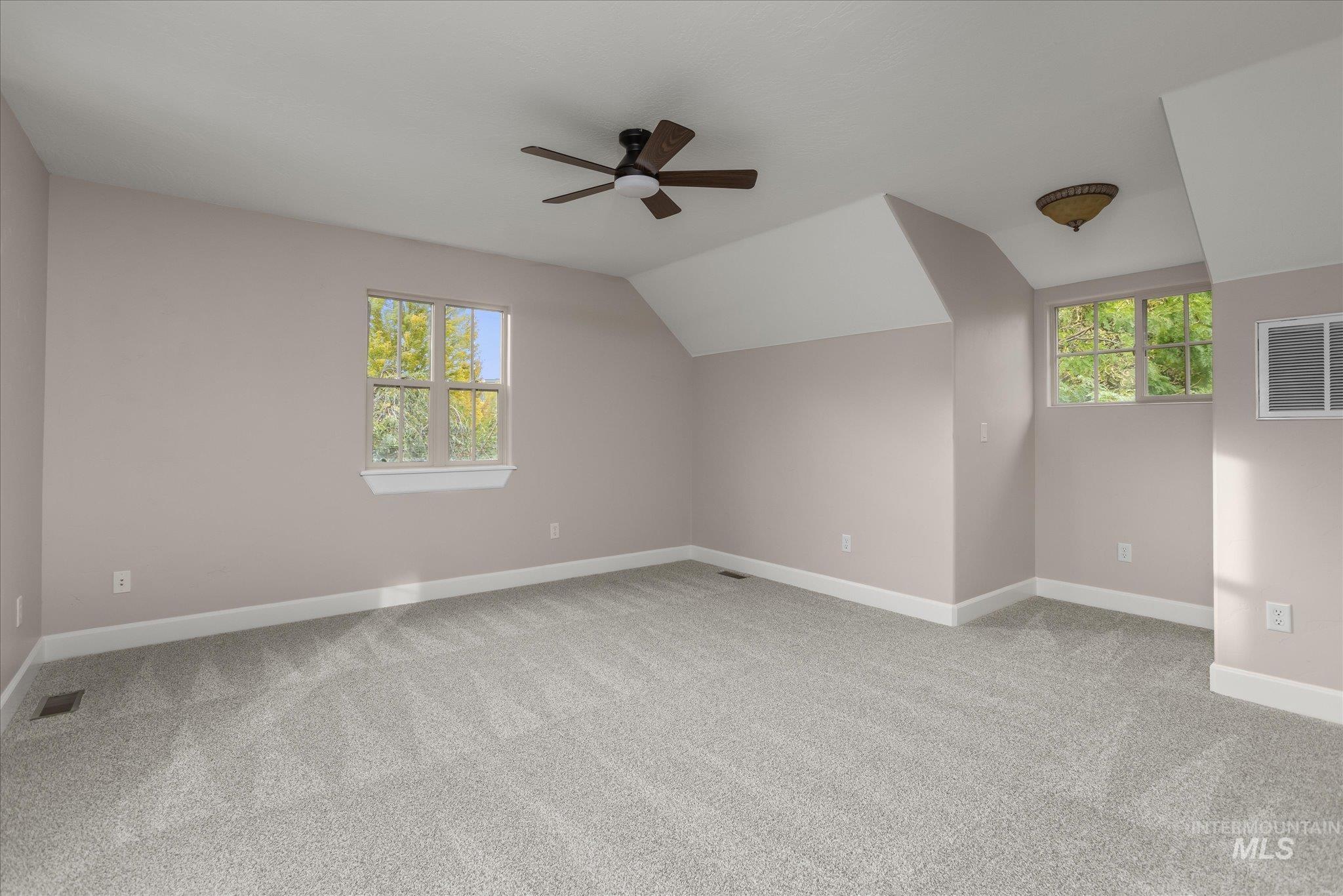 Additional living space featuring light colored carpet, lofted ceiling, and a ceiling fan